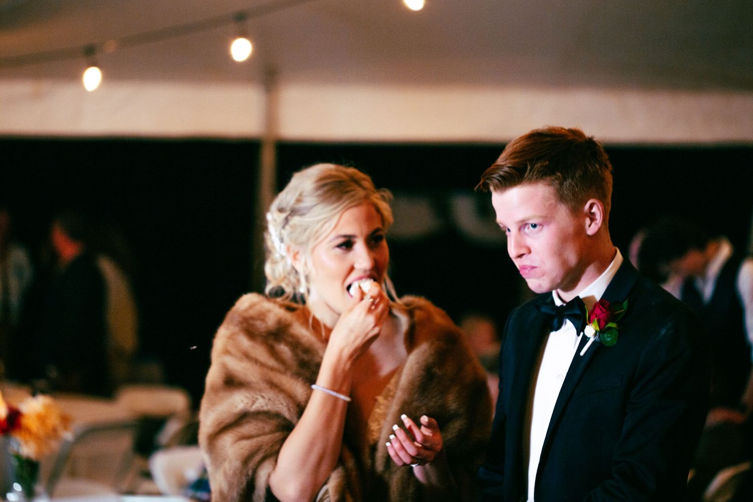 bride and groom cutting cake and taking first bite at wedding