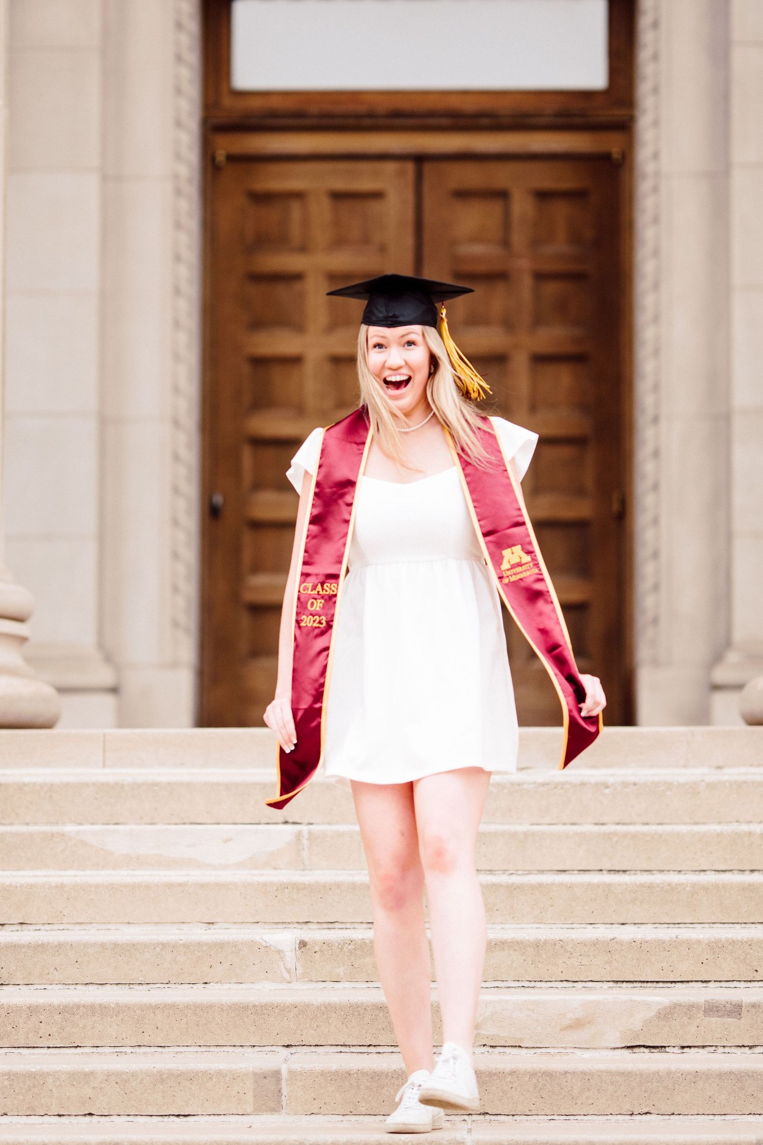university of minnesota graduate in white dress with sash
