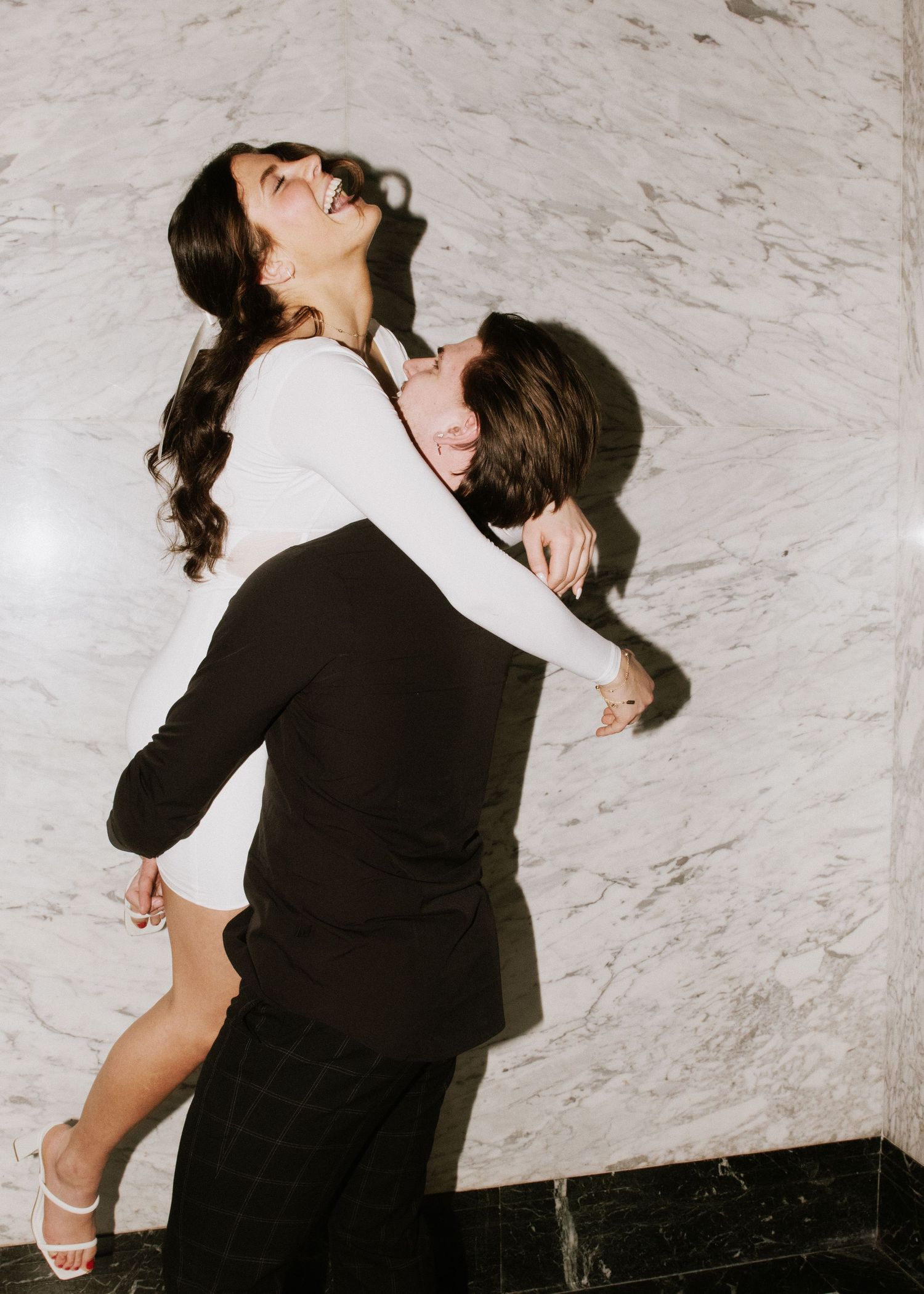 engagement photo of couple with direct flash in front of marble wall at hotel in minneapolis