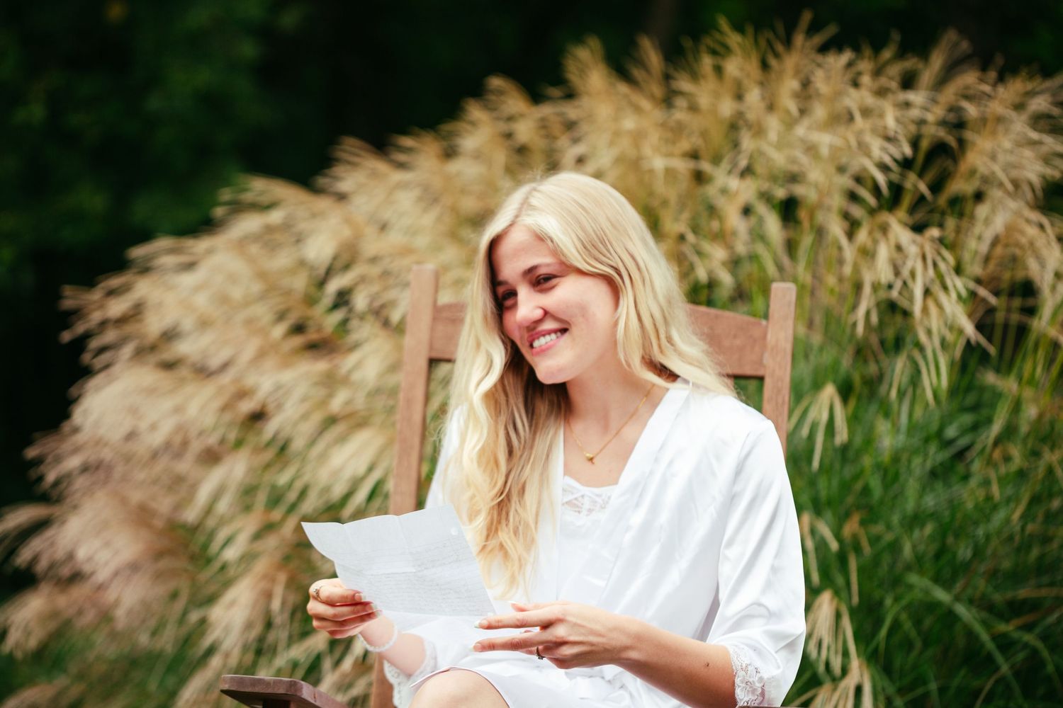 bride sitting in chair reading a letter crying