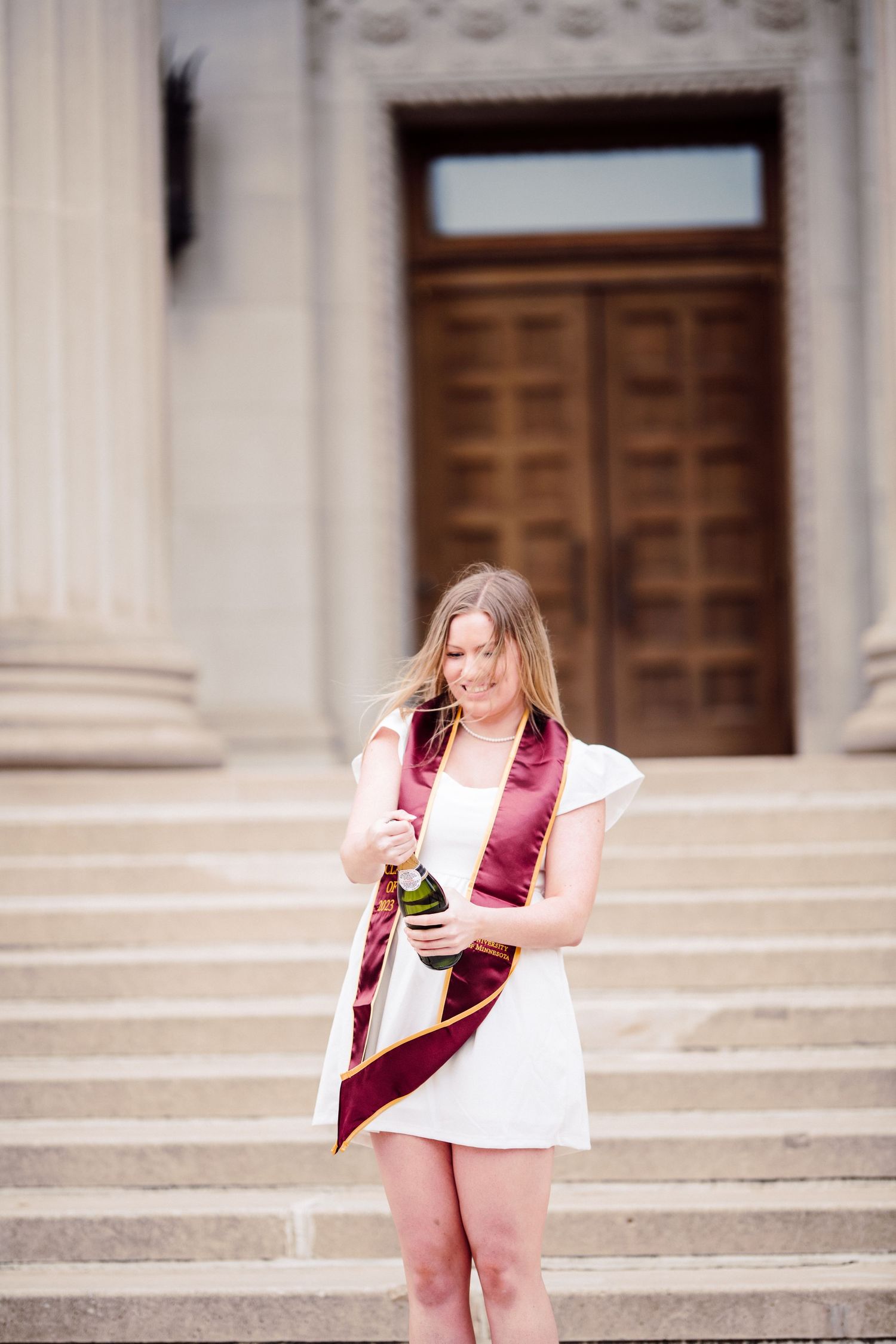 university of minnesota graduate in white dress with sash