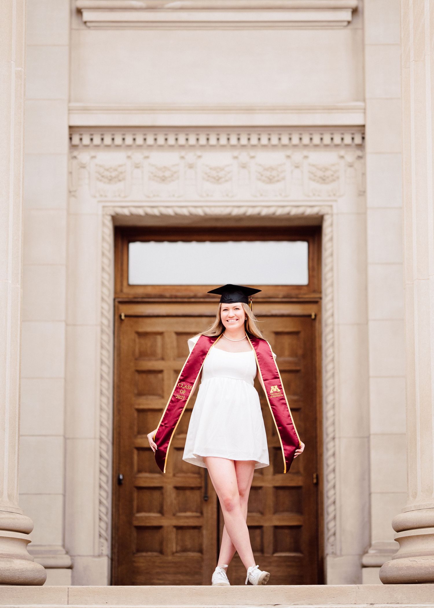 university of minnesota graduate in white dress with sash