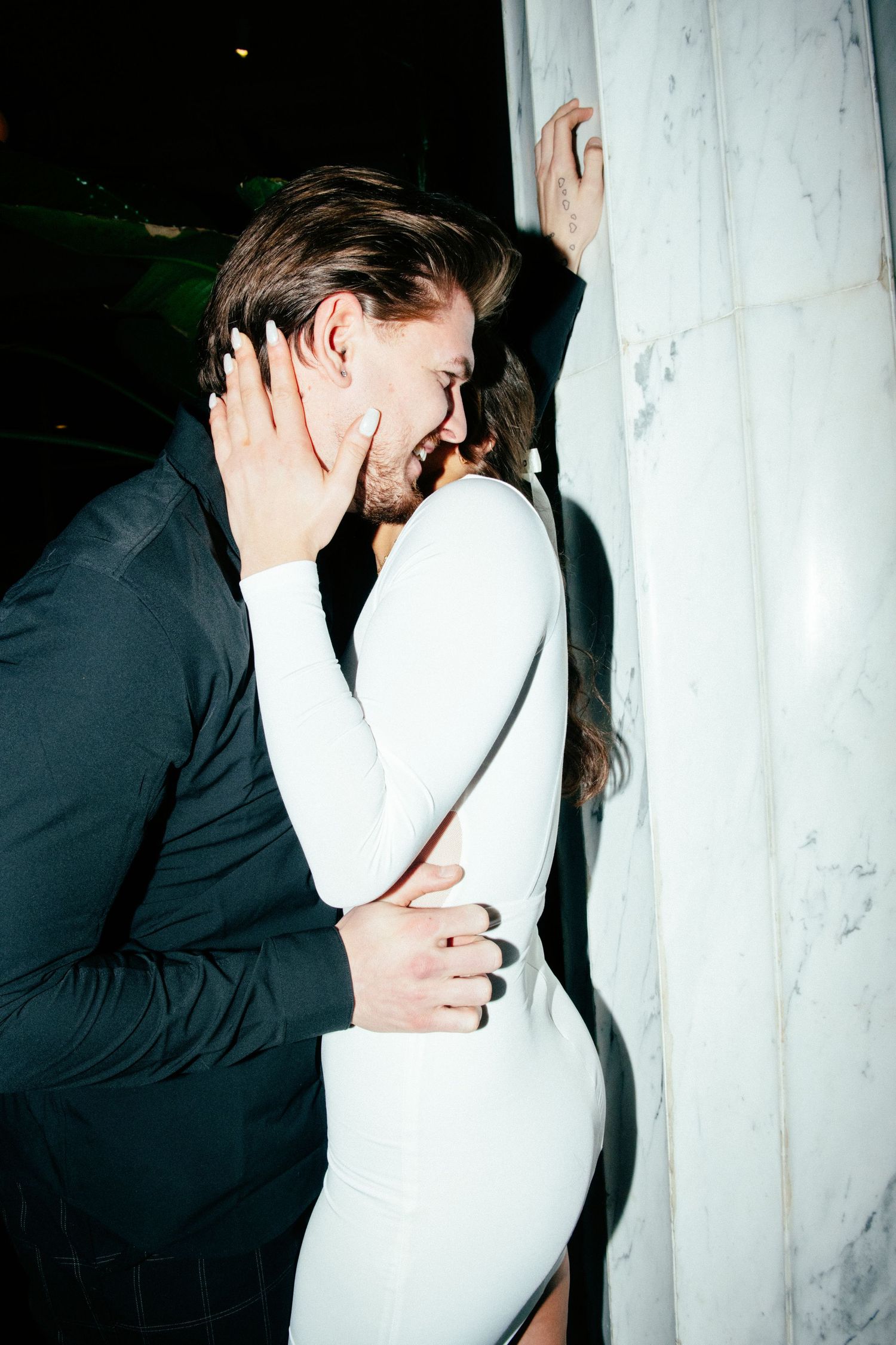 engagement photo of couple with direct flash in front of marble wall at hotel in minneapolis