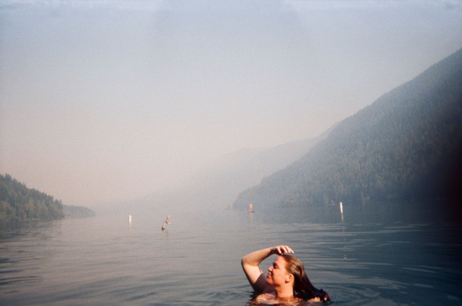 film photo of girl swimming in lake in between mountains