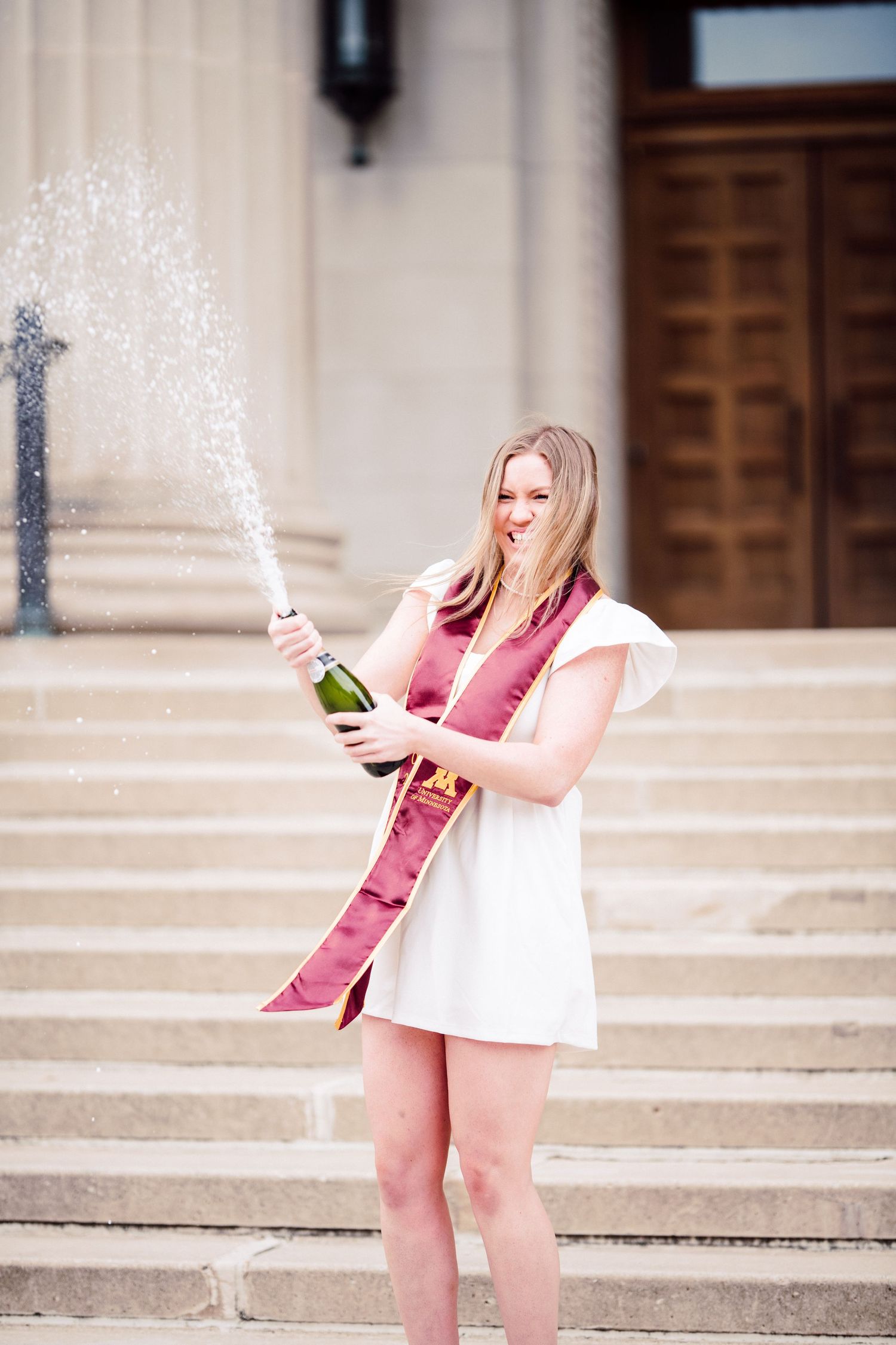 university of minnesota graduate in white dress with sash
