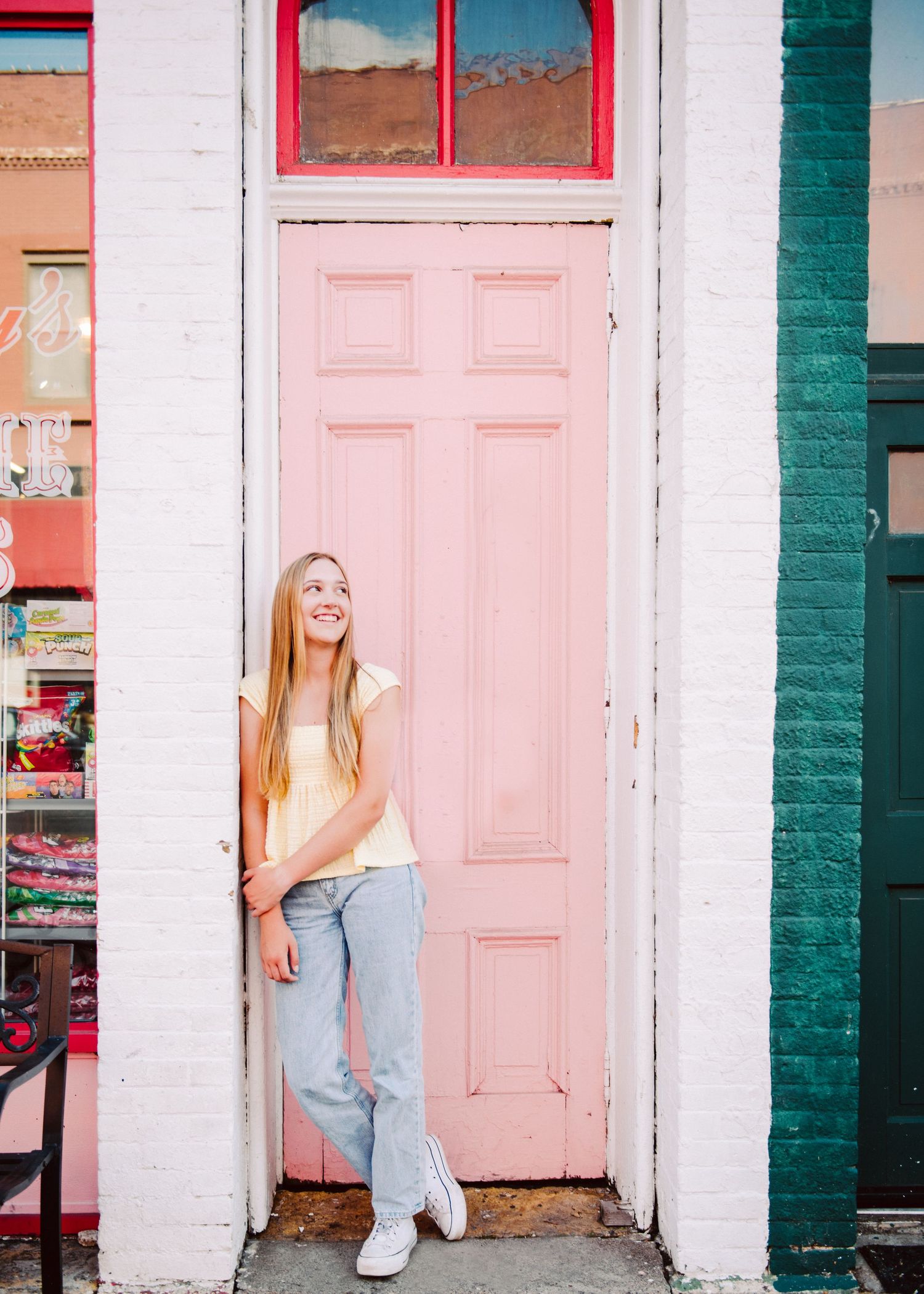 high school senior girl pictures leaning against pink door