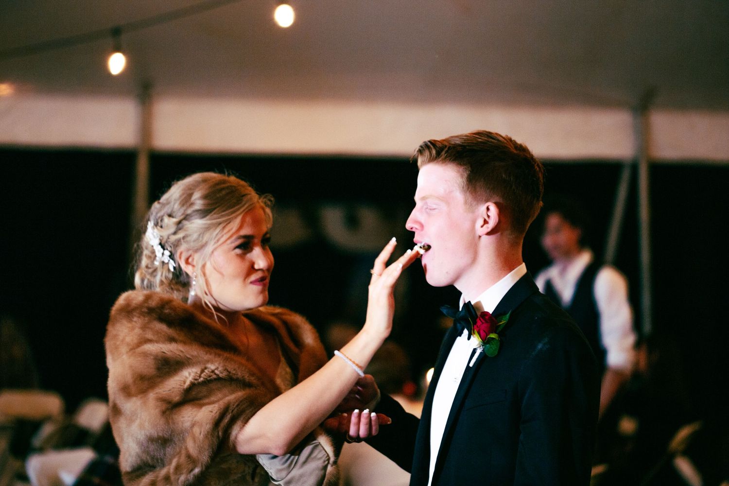bride and groom cutting cake and taking first bite at wedding