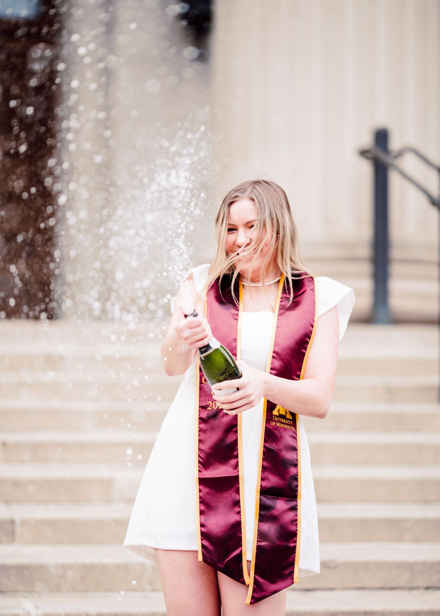 university of minnesota graduate in white dress with sash