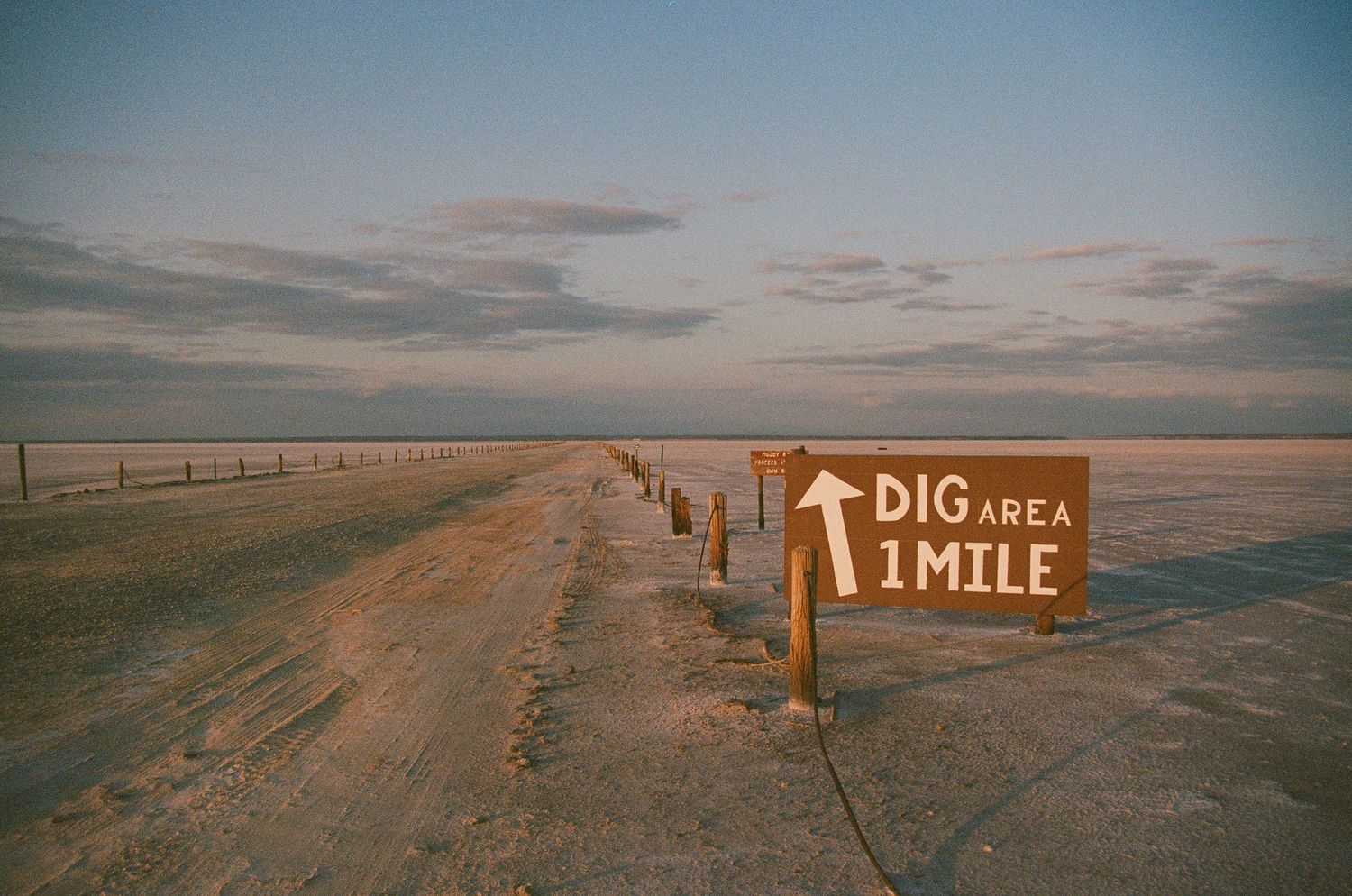 film photo of sign that says dig area 1 mile in desert