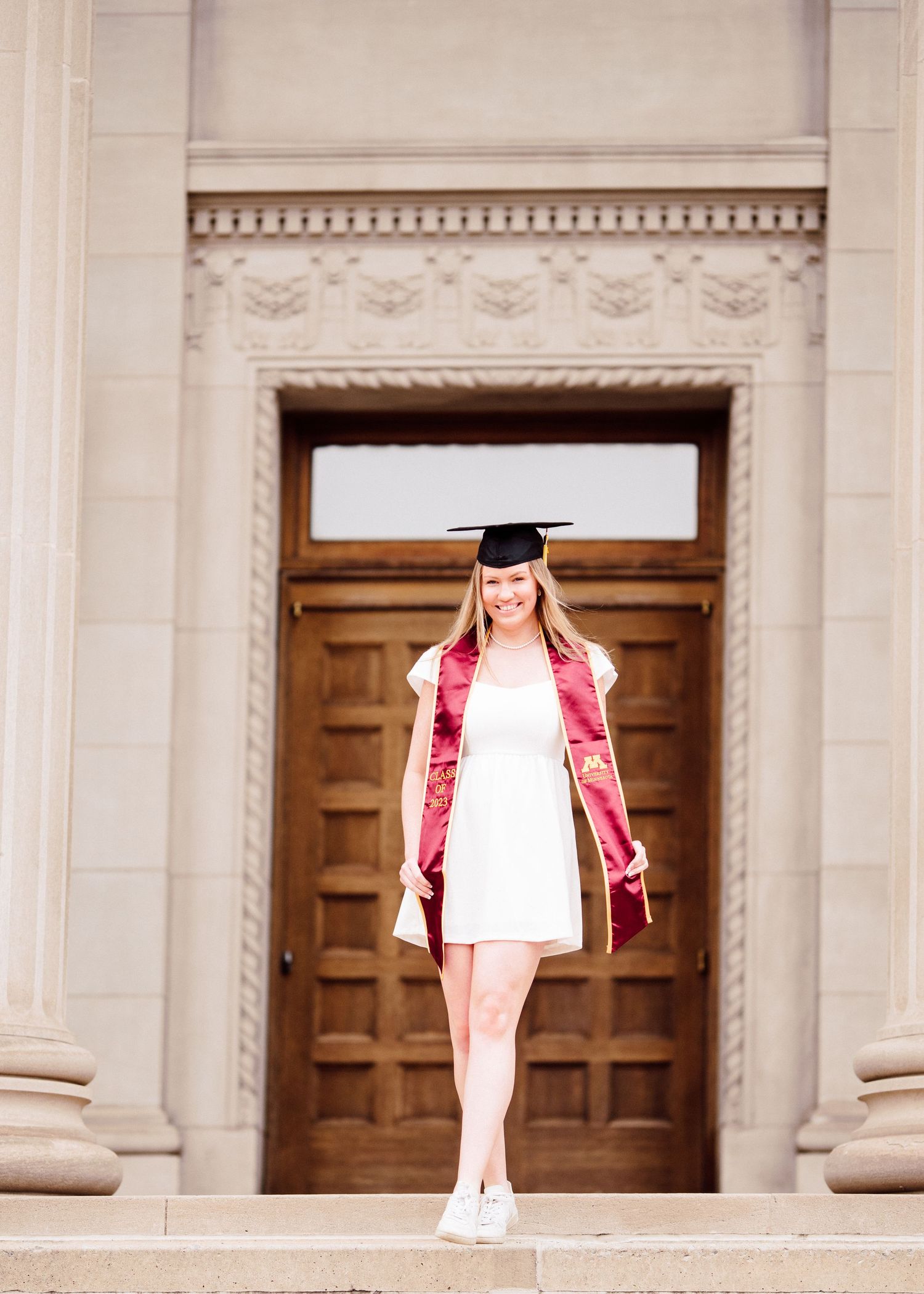 university of minnesota graduate in white dress with sash