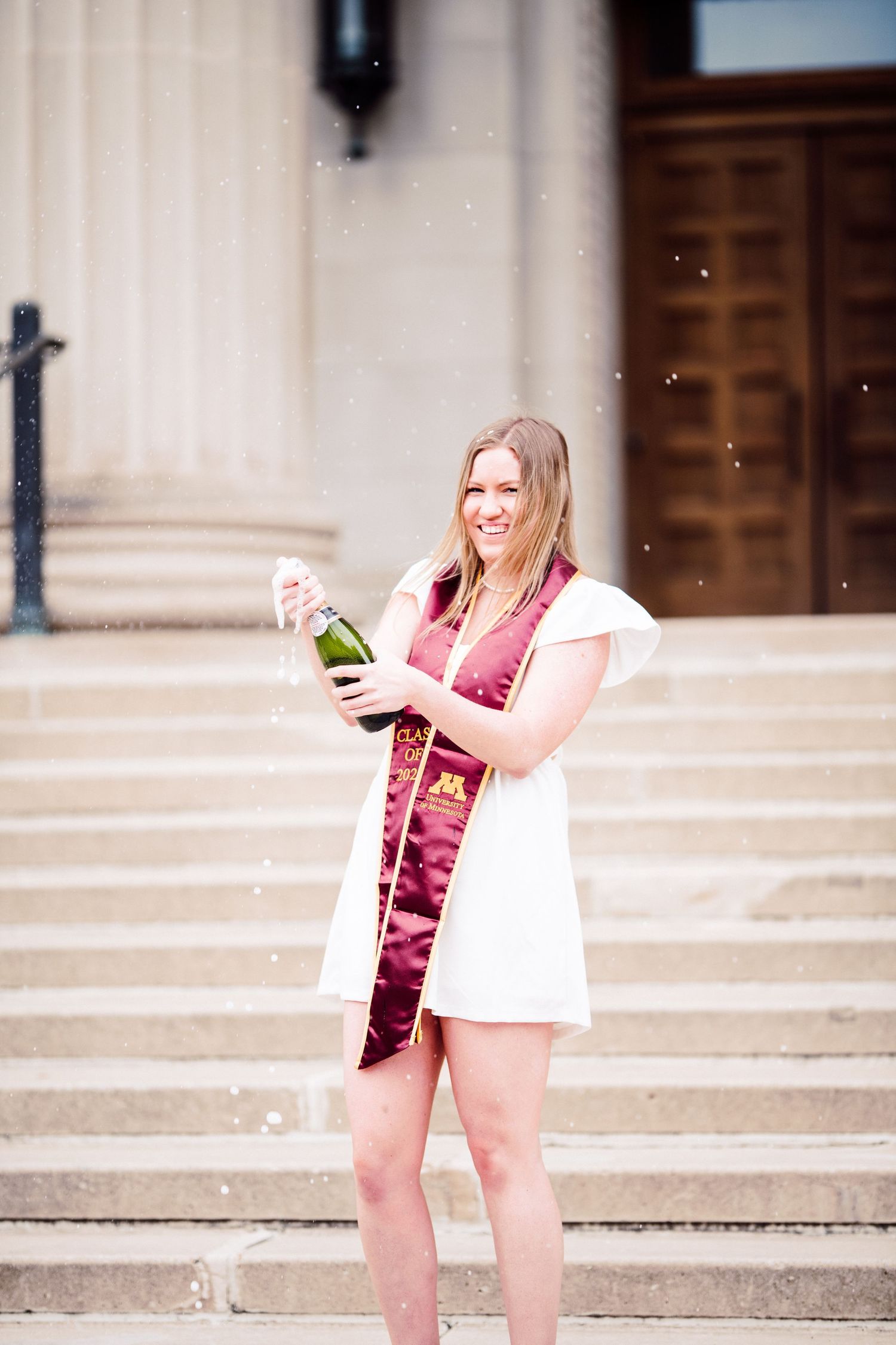 university of minnesota graduate in white dress with sash