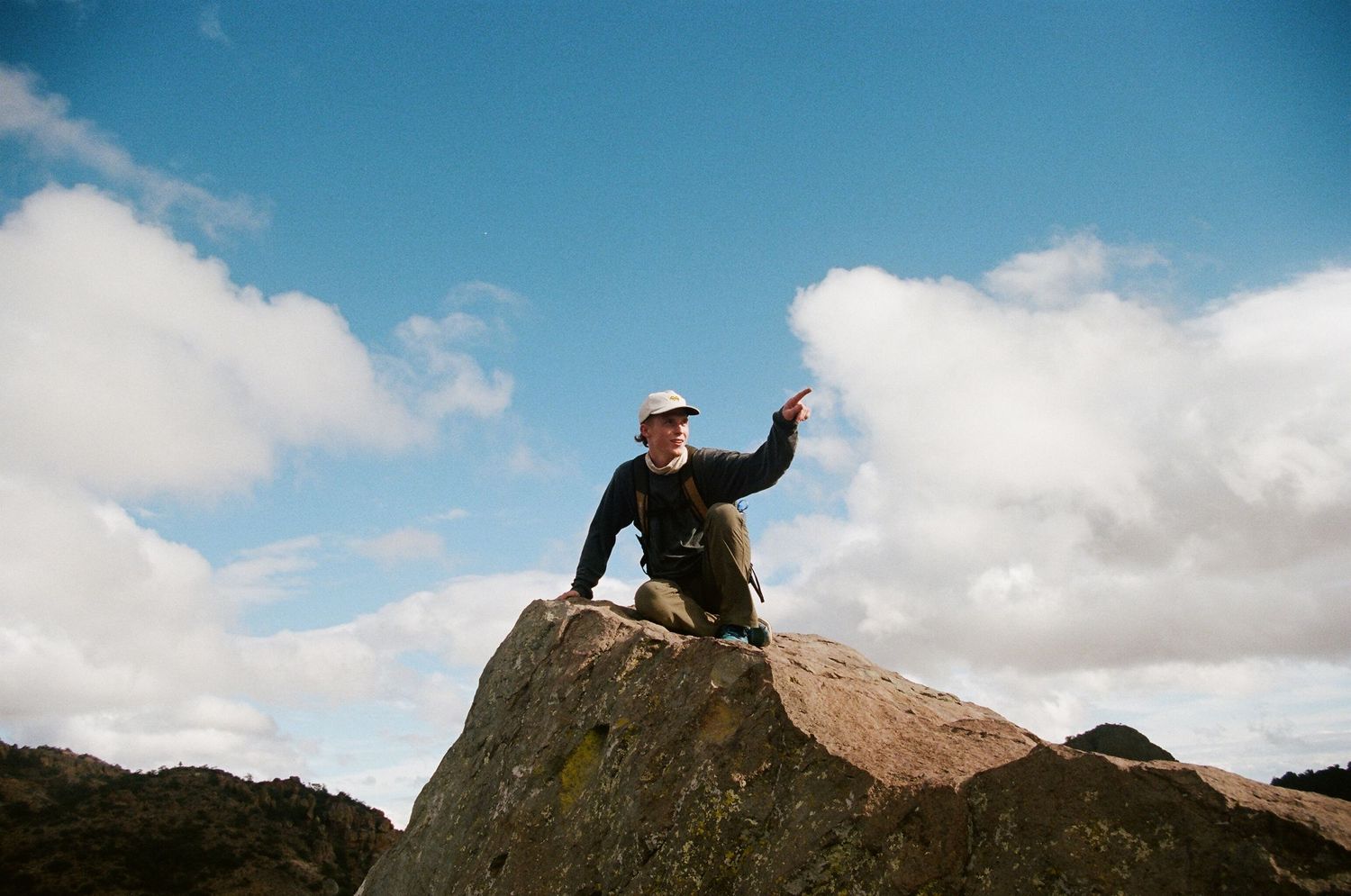 film photo of man on top of mountain pointing