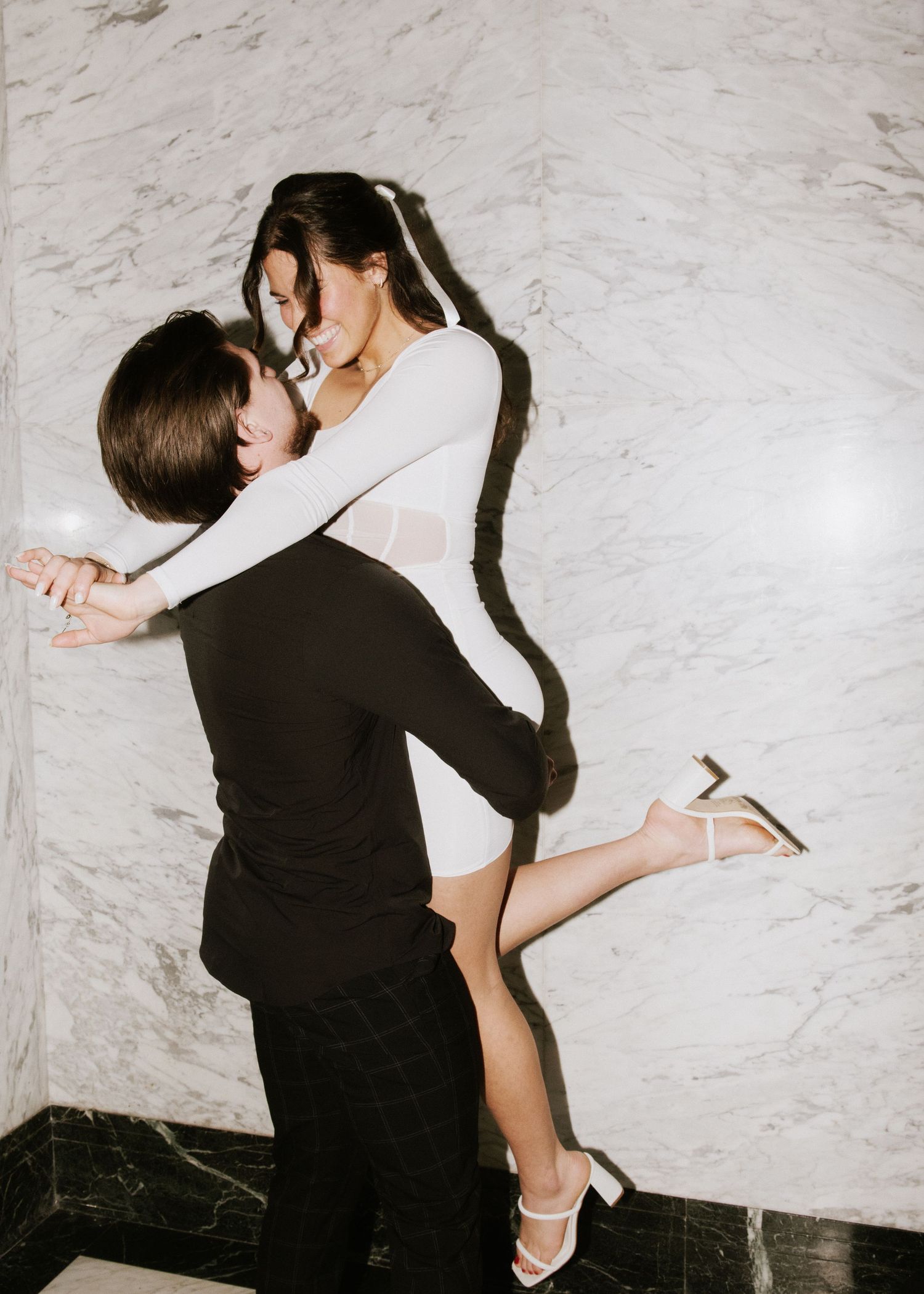 engagement photo of couple with direct flash in front of marble wall at hotel in minneapolis