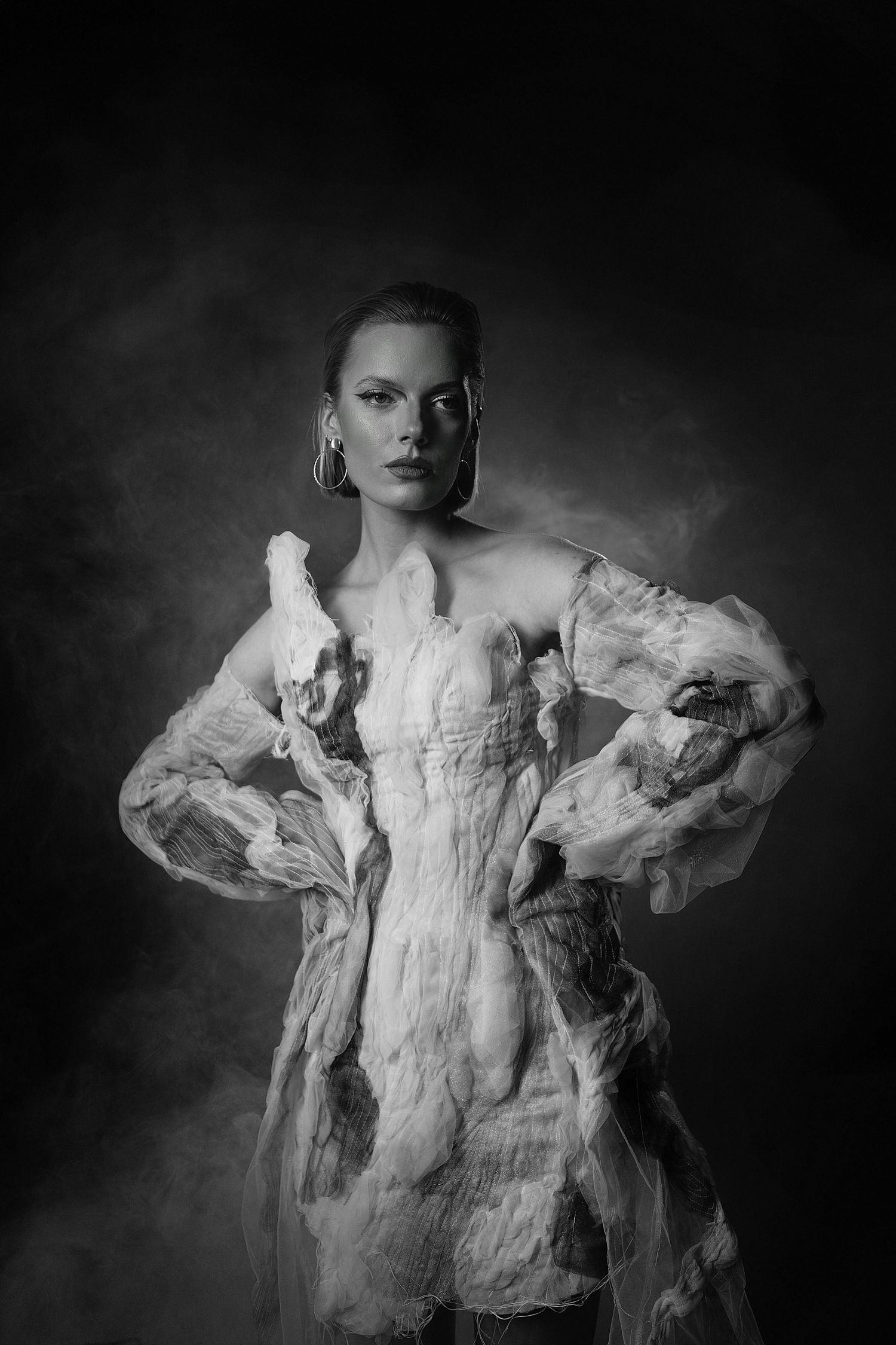 Dramatic black and white portrait series featuring ethereal white fabric against dark background creating ghostly silhouettes.