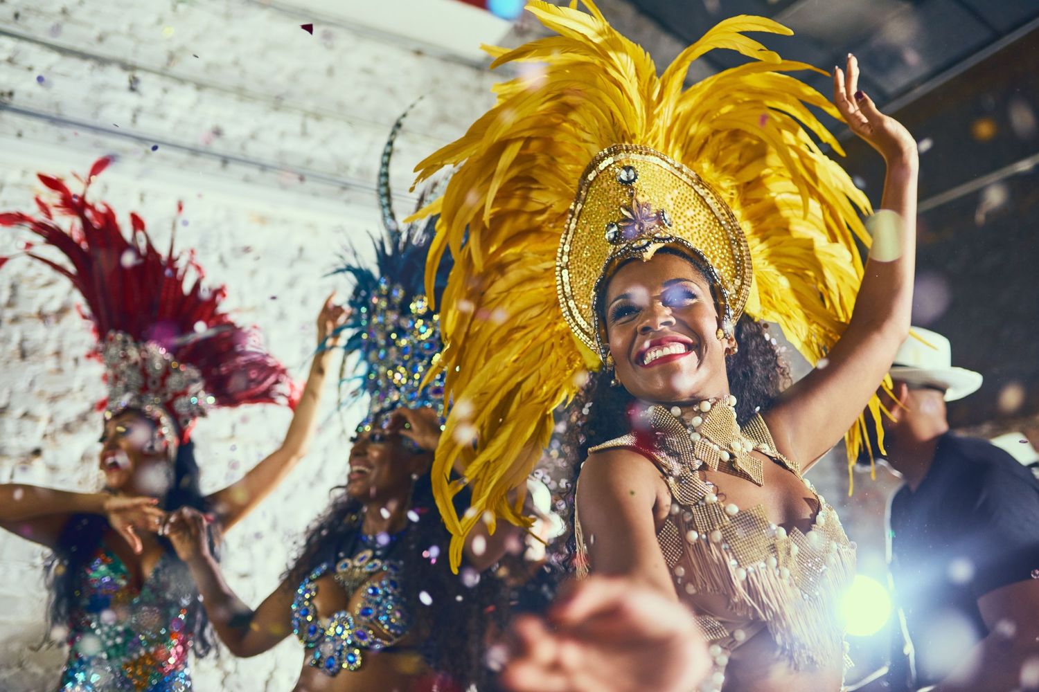 Samba dancers in vibrant yellow feathered costumes perform energetically during a carnival celebration.