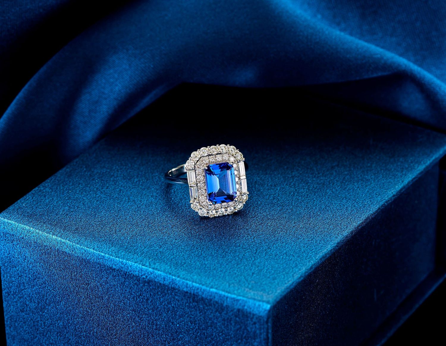 Multiple macro shots of a sparkling diamond ring with blue sapphire stone against a dark blue background.