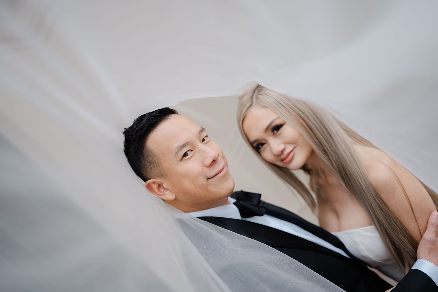 A joyful wedding couple shares a laugh during their veil photoshoot.