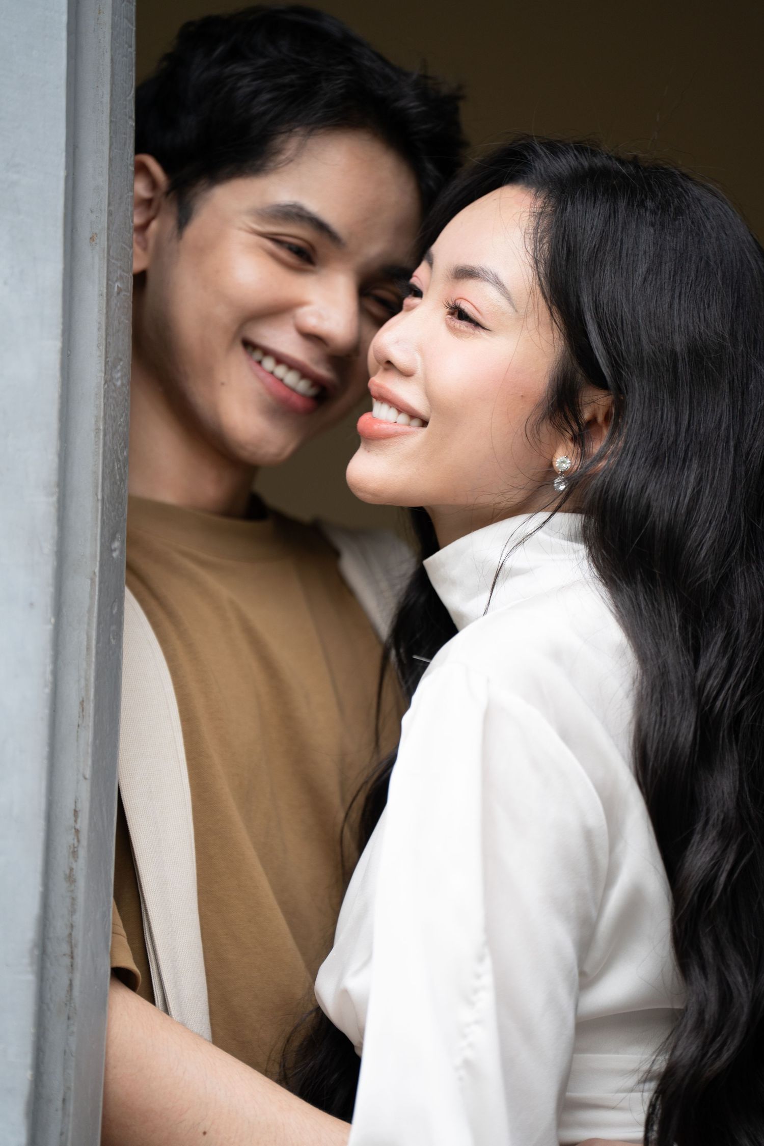 A couple shares intimate moments while wearing brown and white outfits in an indoor setting.