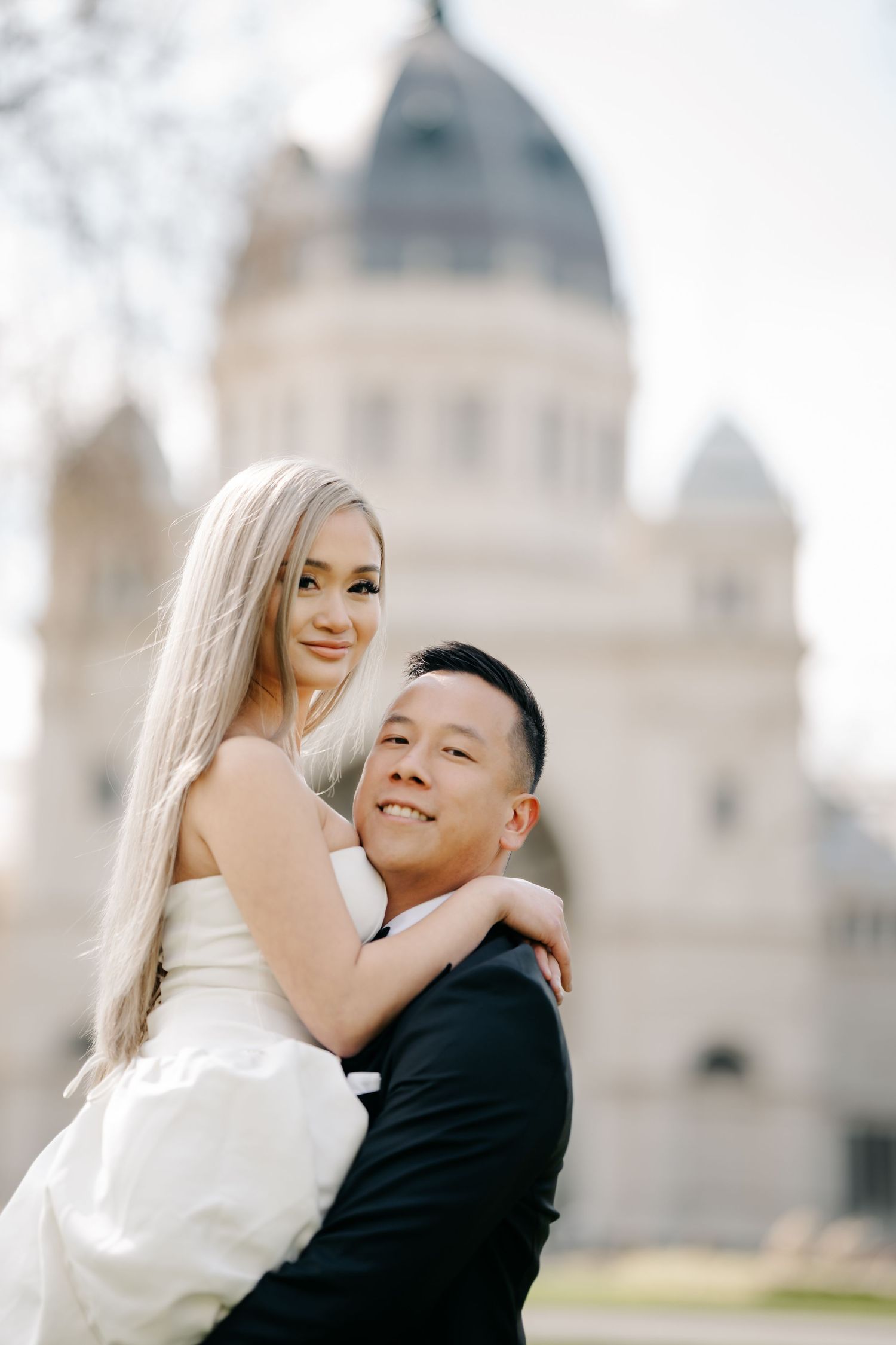 A loving couple poses for their wedding photos in front of a grand domed building.
