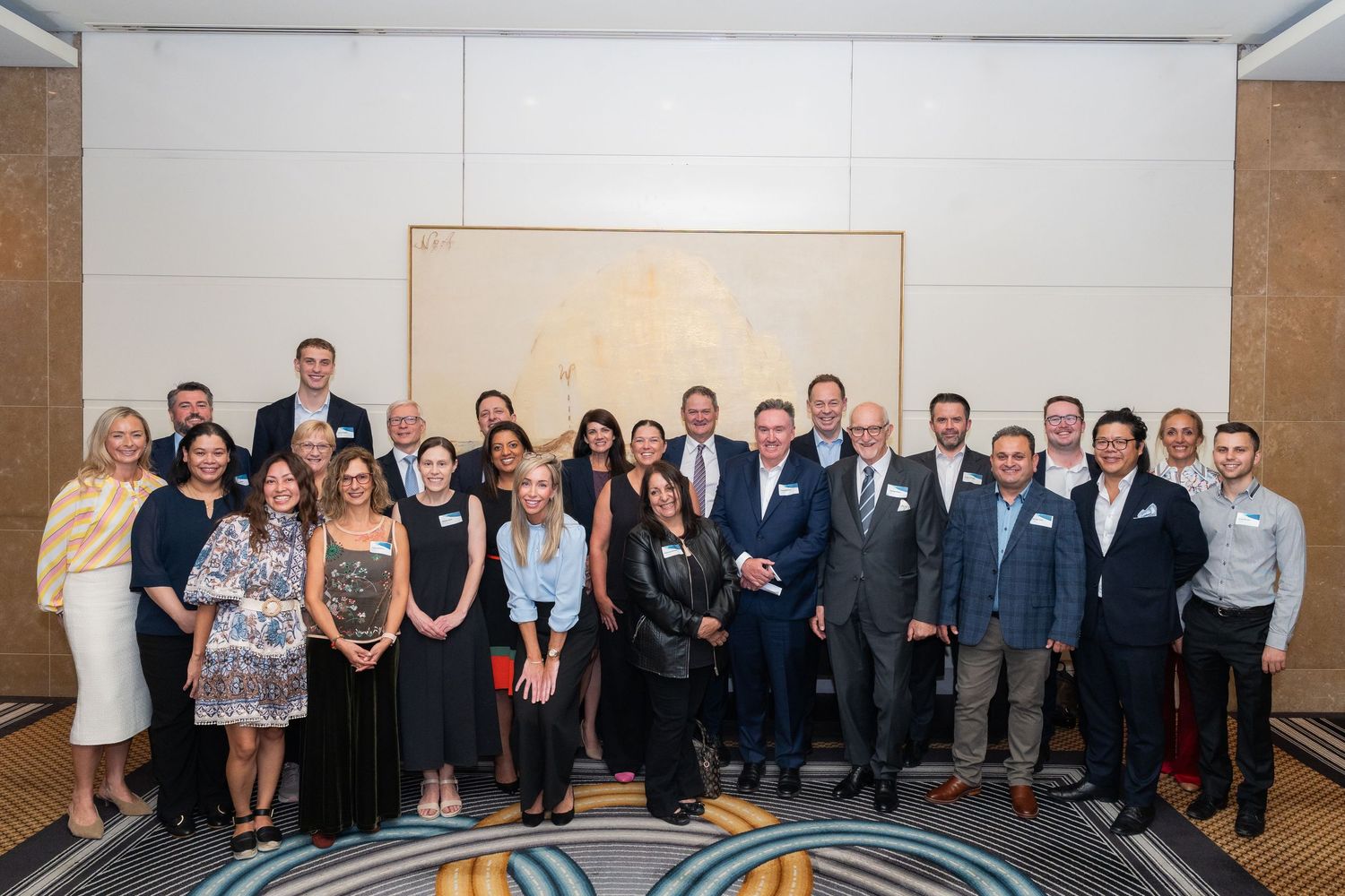 Large group of business professionals posing together at a corporate event in elegant venue.