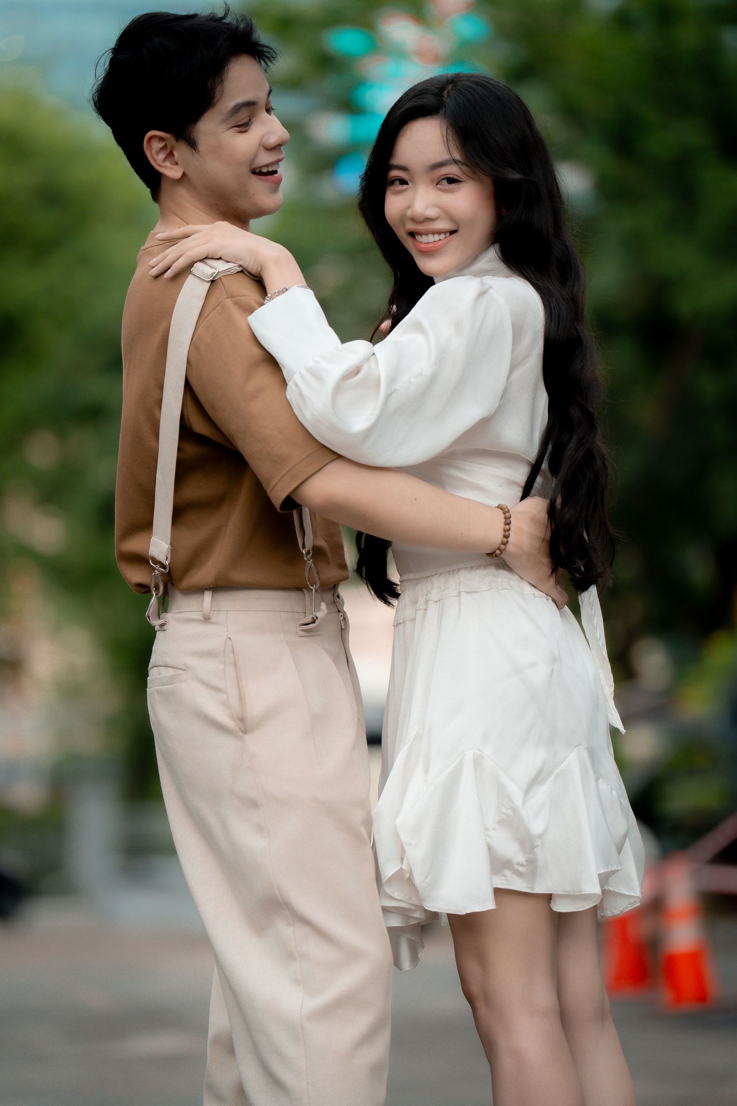 A couple laughs together while embracing in a casual outdoor photoshoot.