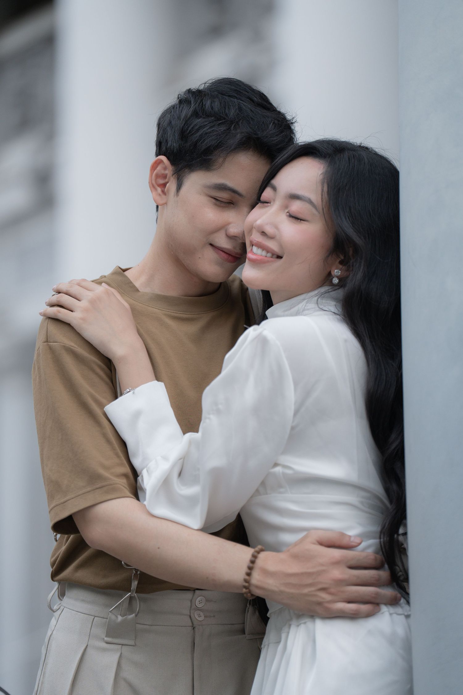 Intimate couple embracing in casual attire against a light background.