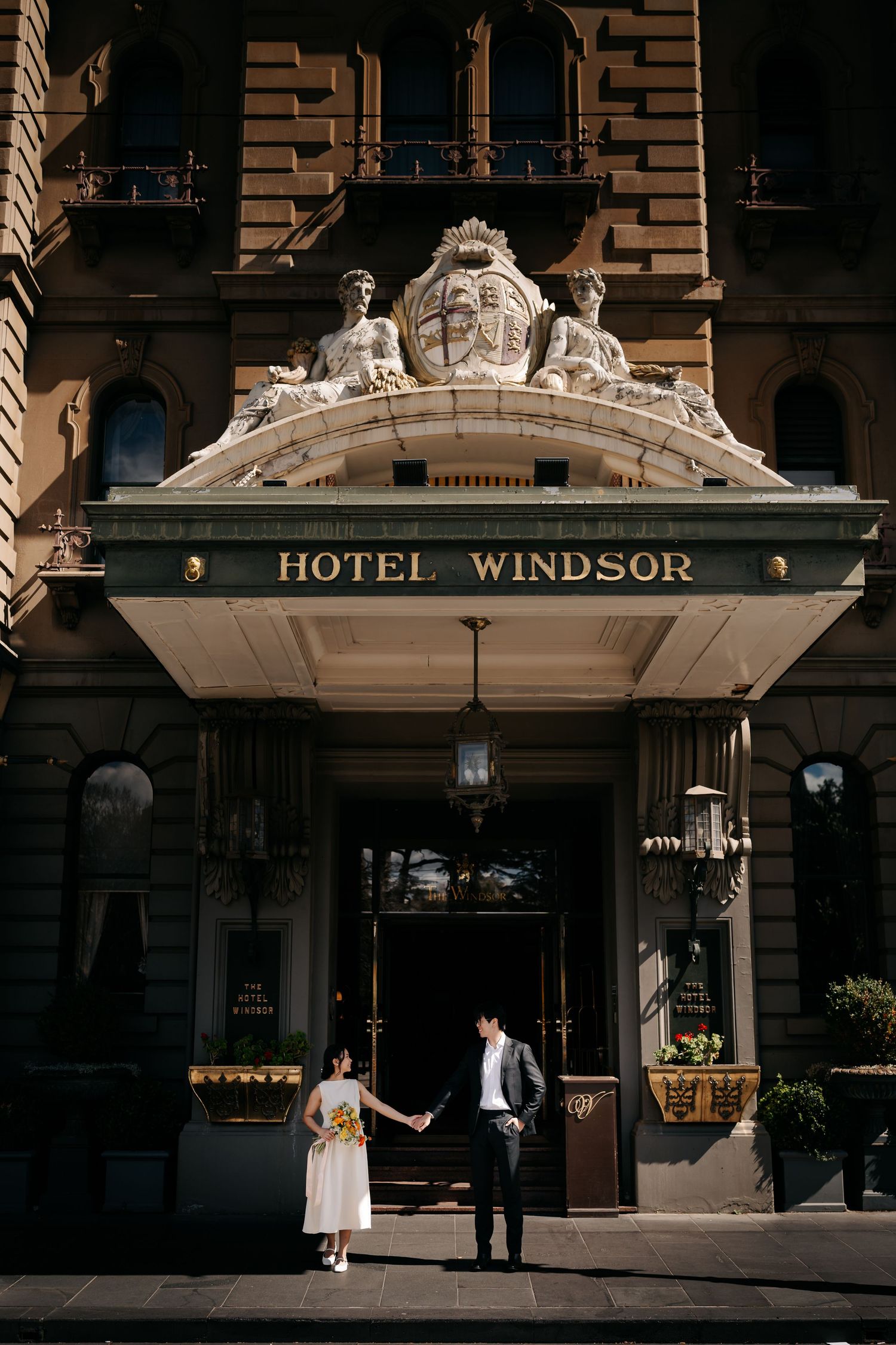 Couple poses beneath the ornate Hotel Windsor signage and architectural details.