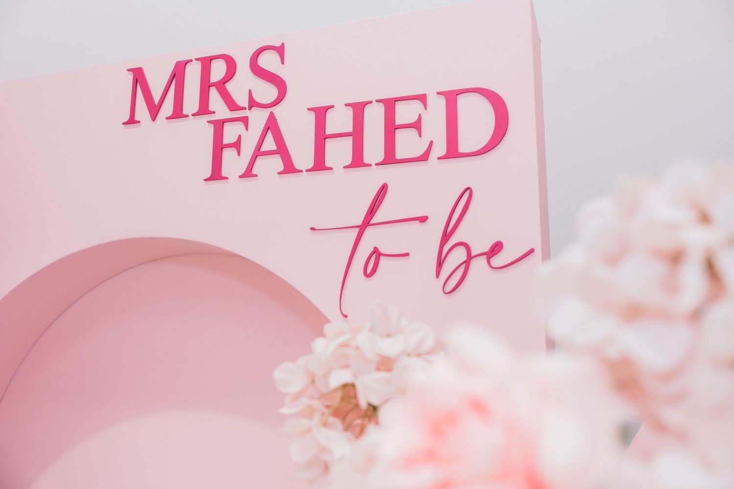 Pink bridal shower sign reading Mrs Fahed To Be with elegant script lettering and floral decorations.