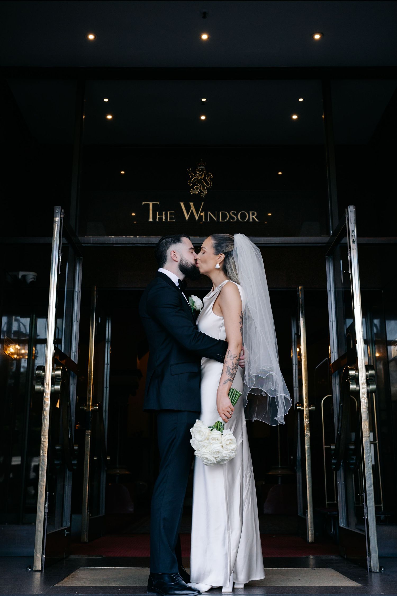 Romantic wedding portrait of couple sharing an intimate moment at The Windsor hotel entrance.