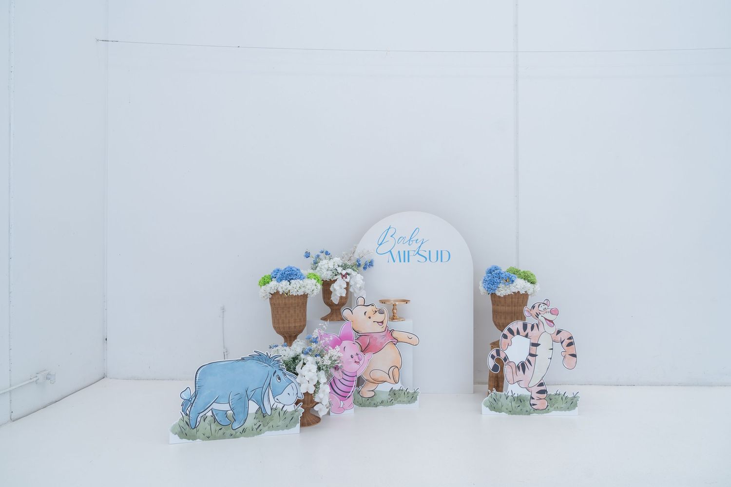 Decorative baby shower display with cartoon animal figurines and an arch sign reading Baby Amelio against a white background.