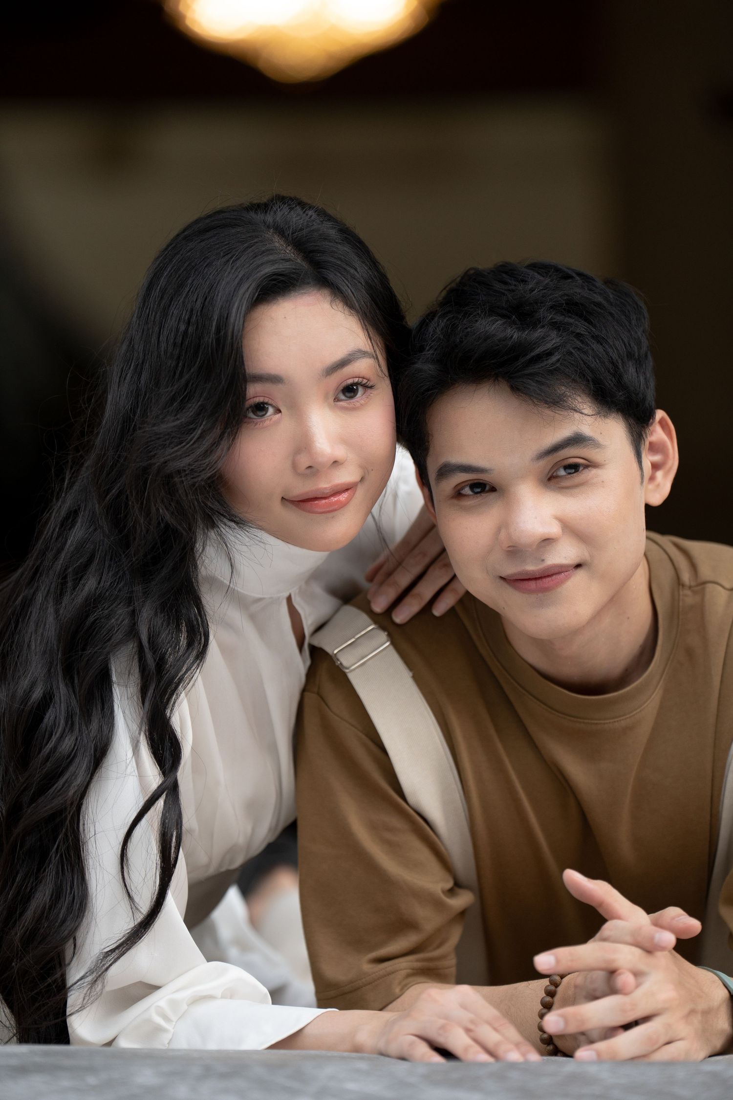 A couple lying down shares intimate close-up moments while wearing brown and white outfits.