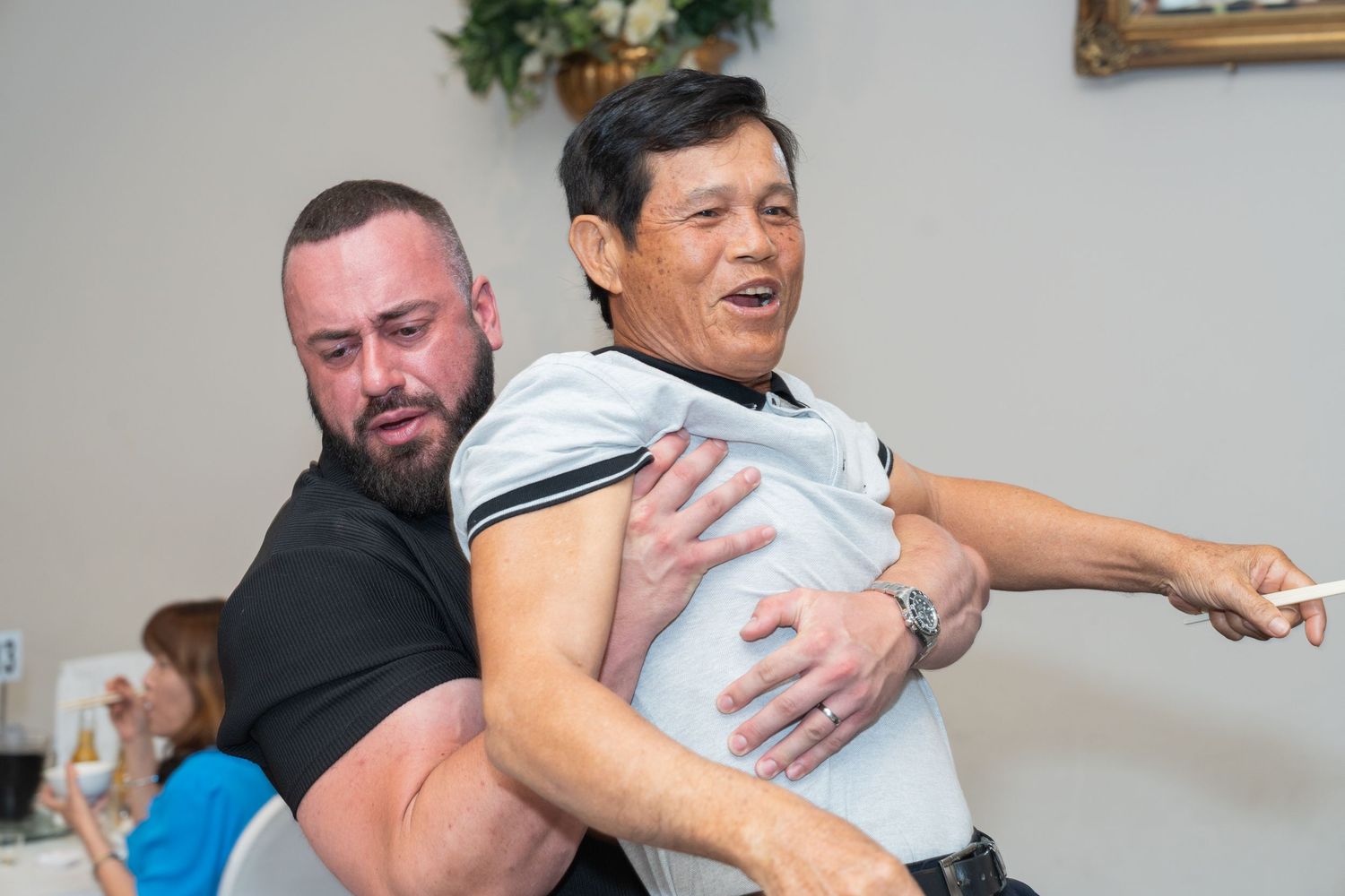 Two men practicing martial arts or self-defense techniques indoors during a training session.