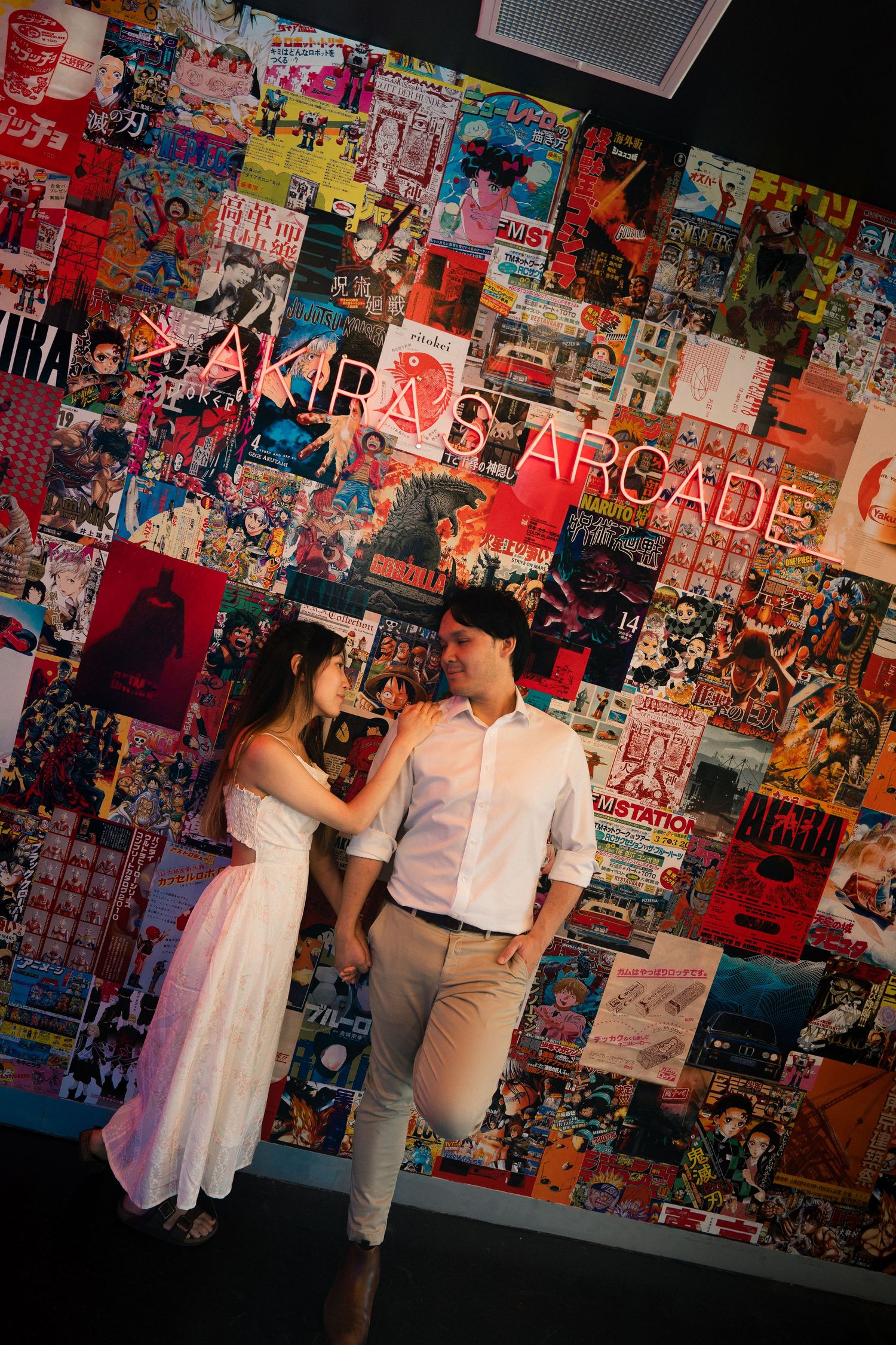 Couple posing in front of colorful anime manga collage wall at Akira's Arcade.