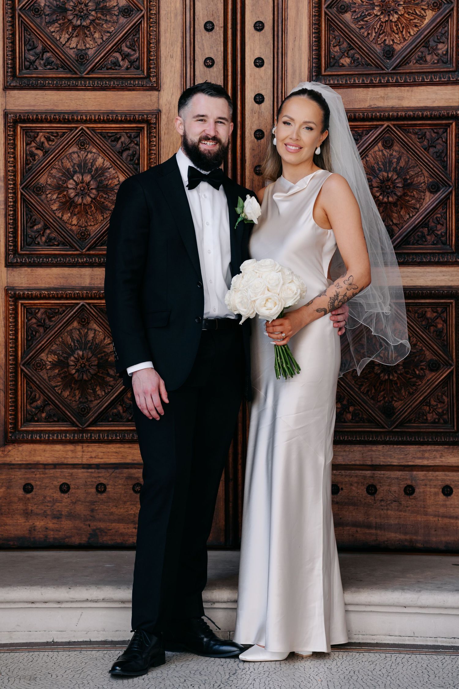 Wedding portraits against ornate wooden paneled wall with intricate carved details.