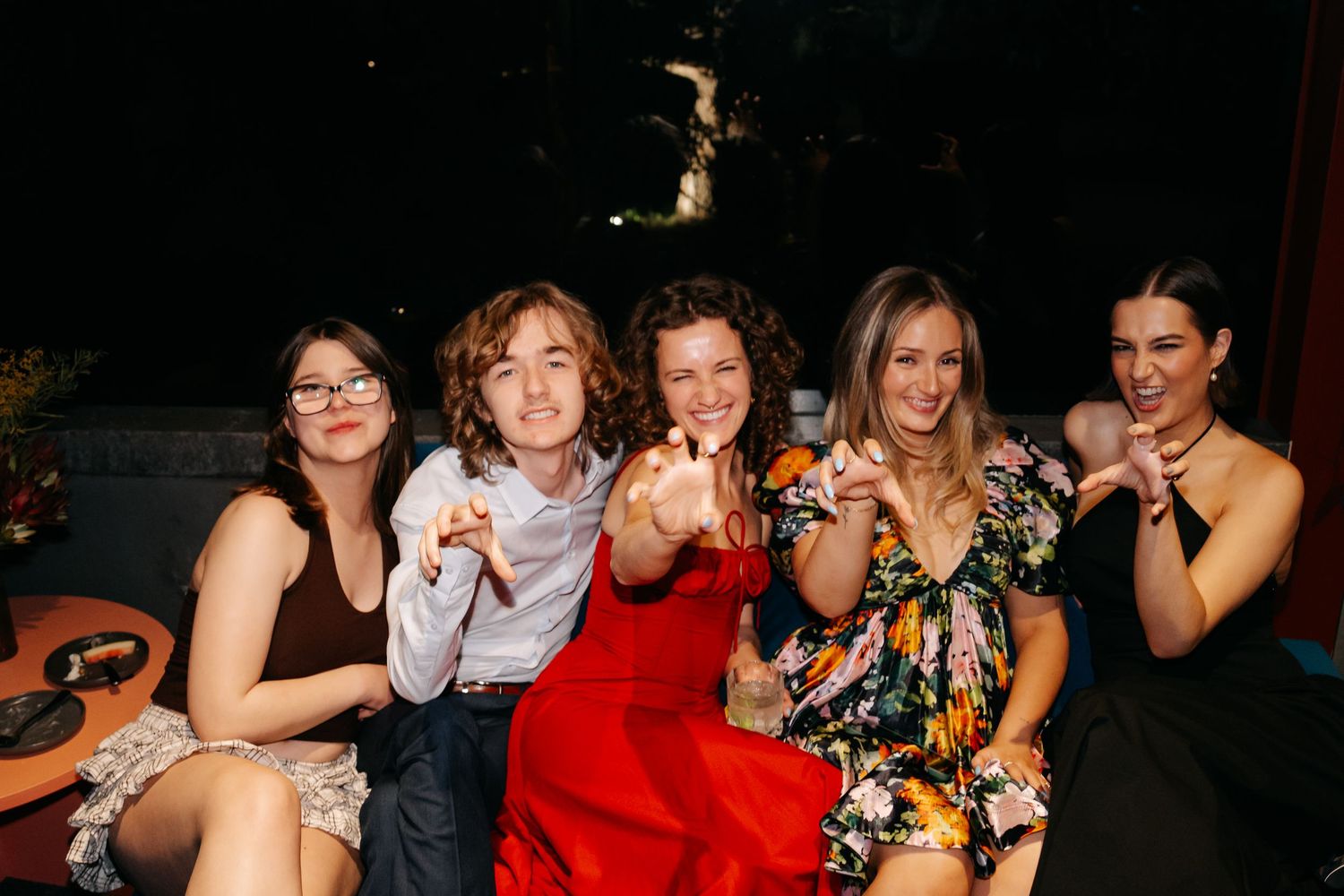 A group of friends pose together for fun party photos in a dark setting.