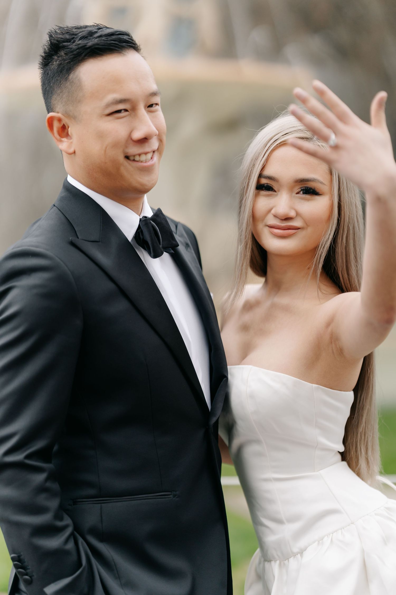 Wedding couple in formal attire posing outdoors with joyful expressions.