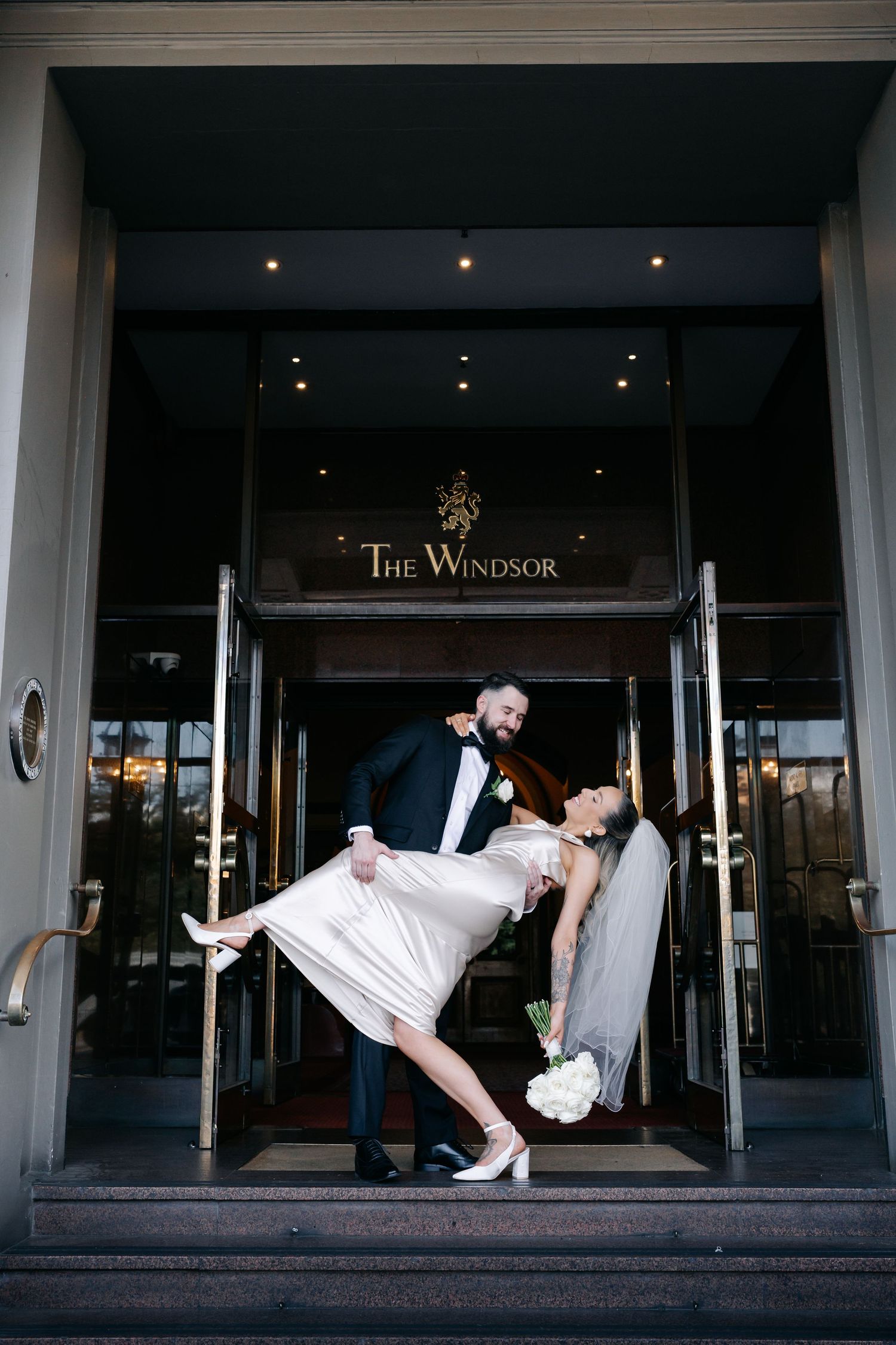 Playful wedding dip pose captured at The Windsor hotel entrance.