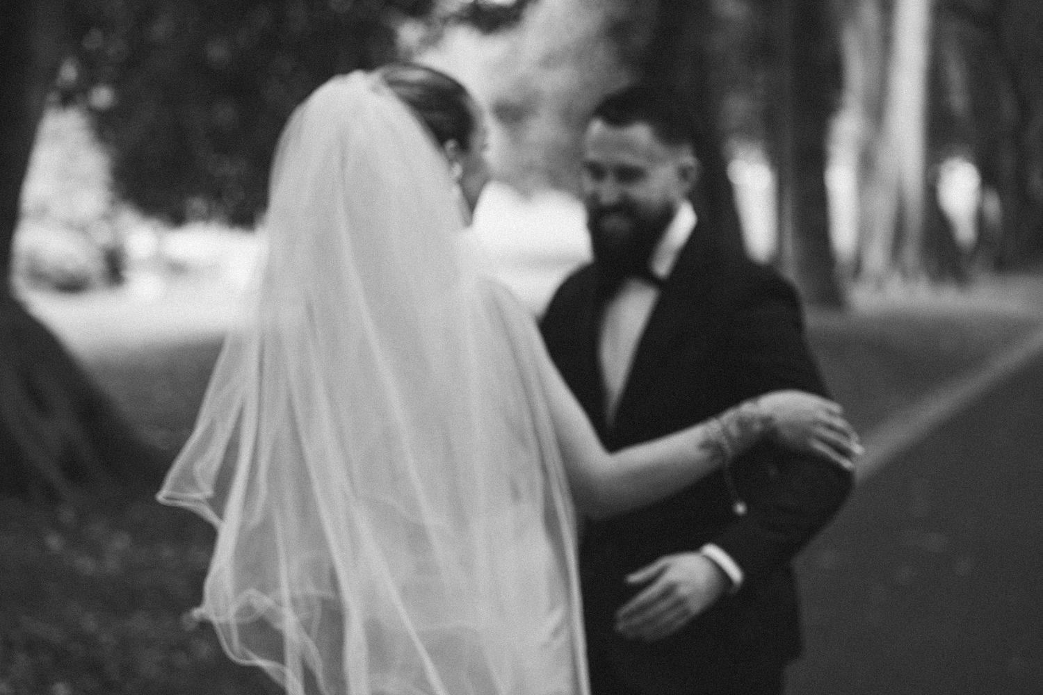 Black and white wedding photo with couple in romantic embrace.