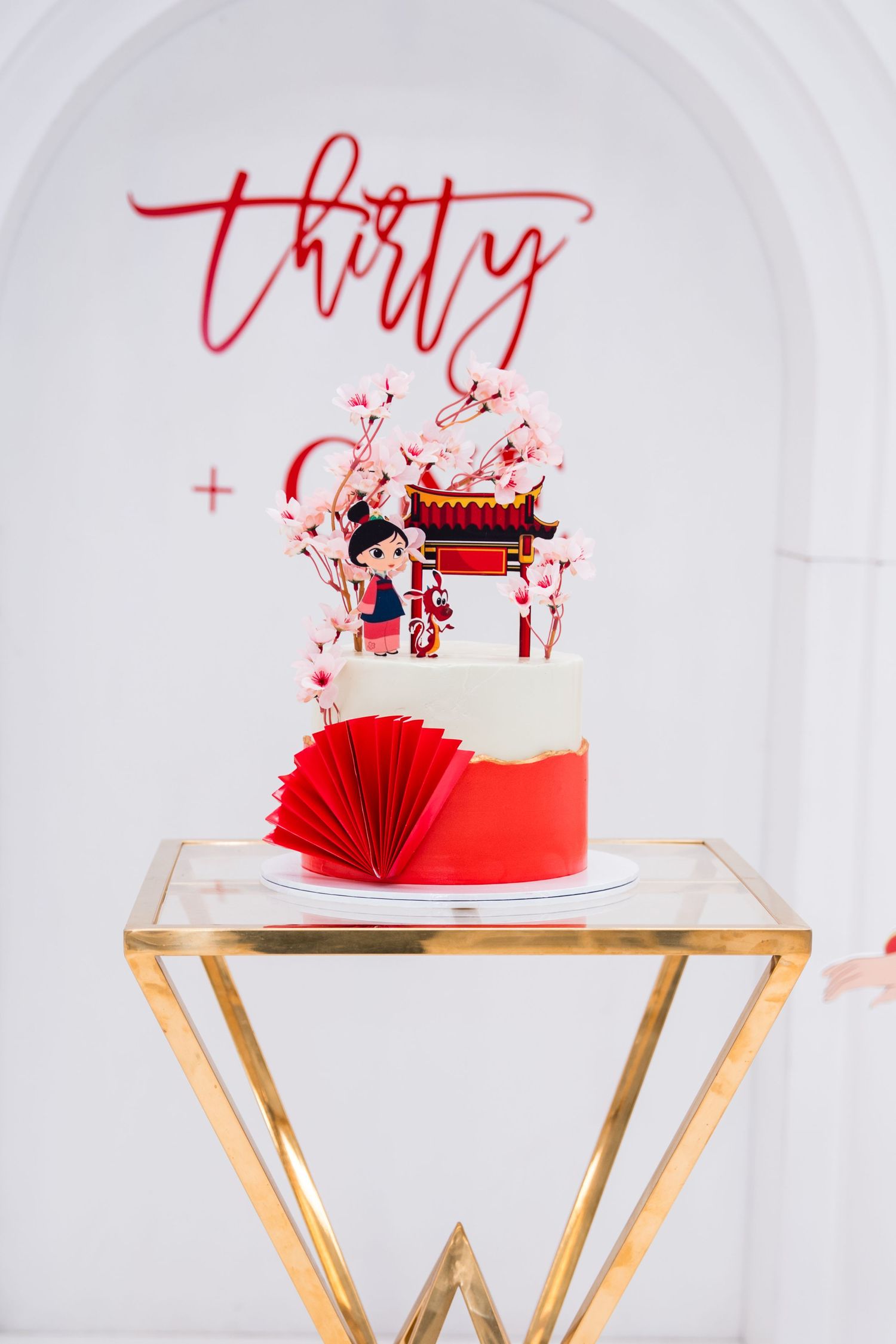 Red and white Chinese-themed birthday cake with Mulan topper, cherry blossoms, and pagoda for a thirtieth celebration.