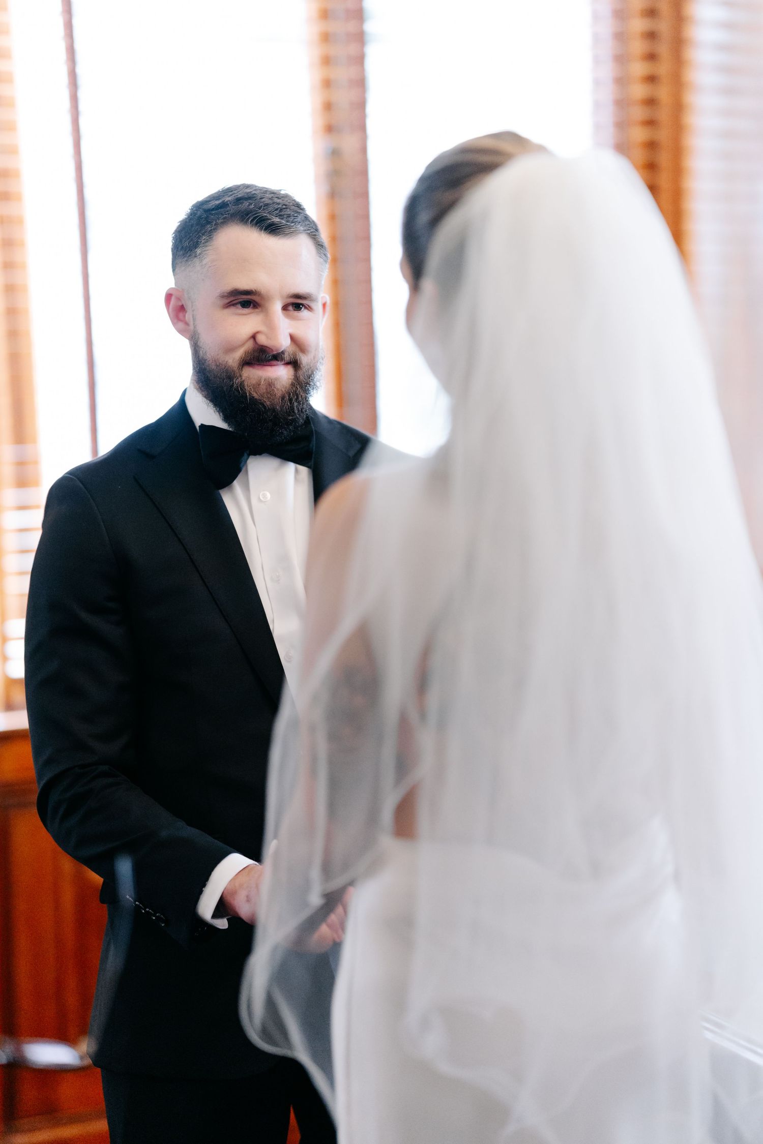 Wedding couple shares sweet moments in an indoor setting with natural window light.
