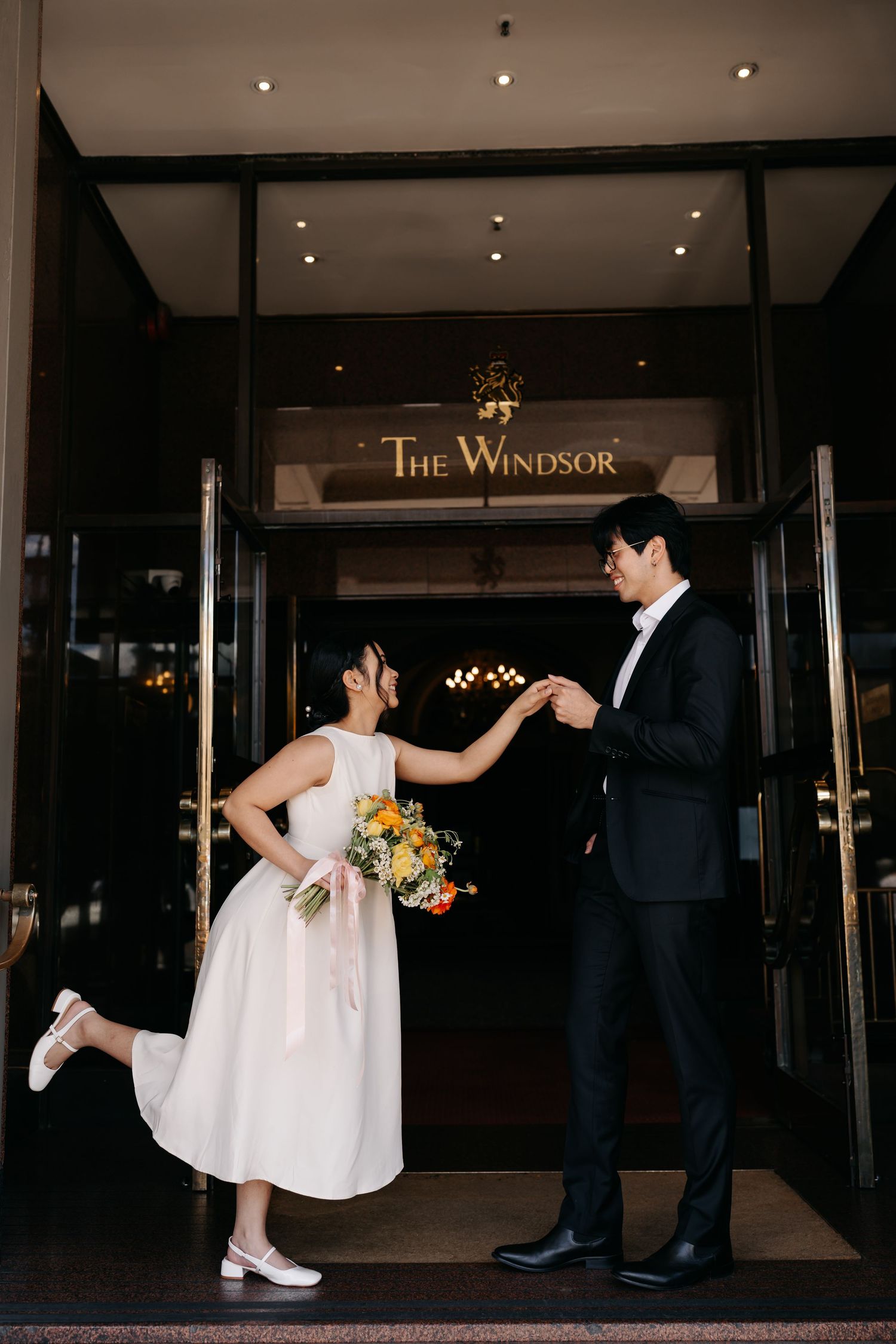 A couple dances playfully outside The Windsor hotel entrance.