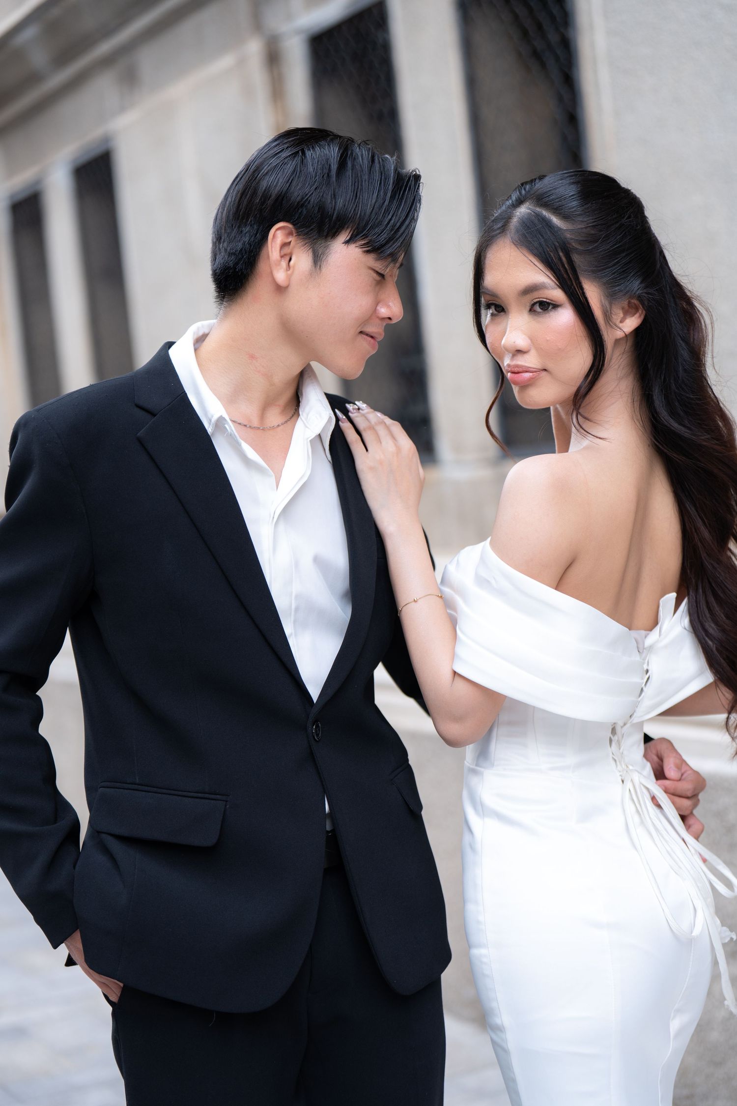 Romantic wedding photography series showing couple in black suit and white dress against stone wall.