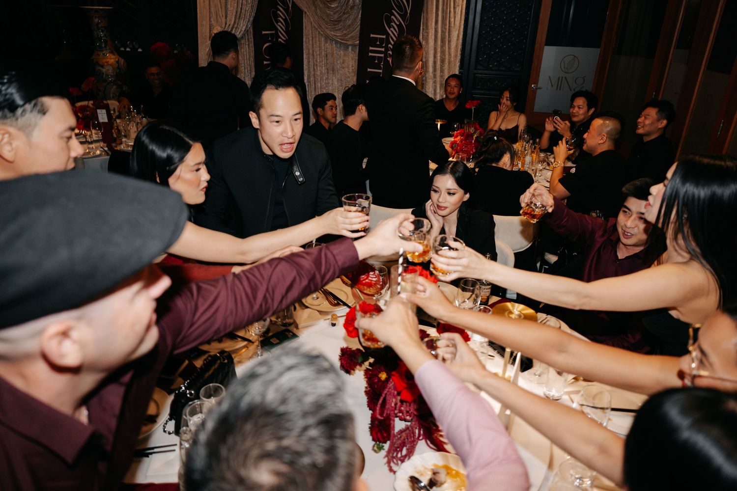 Excited wedding guests clinking glasses in a lively toast at a formal banquet celebration.