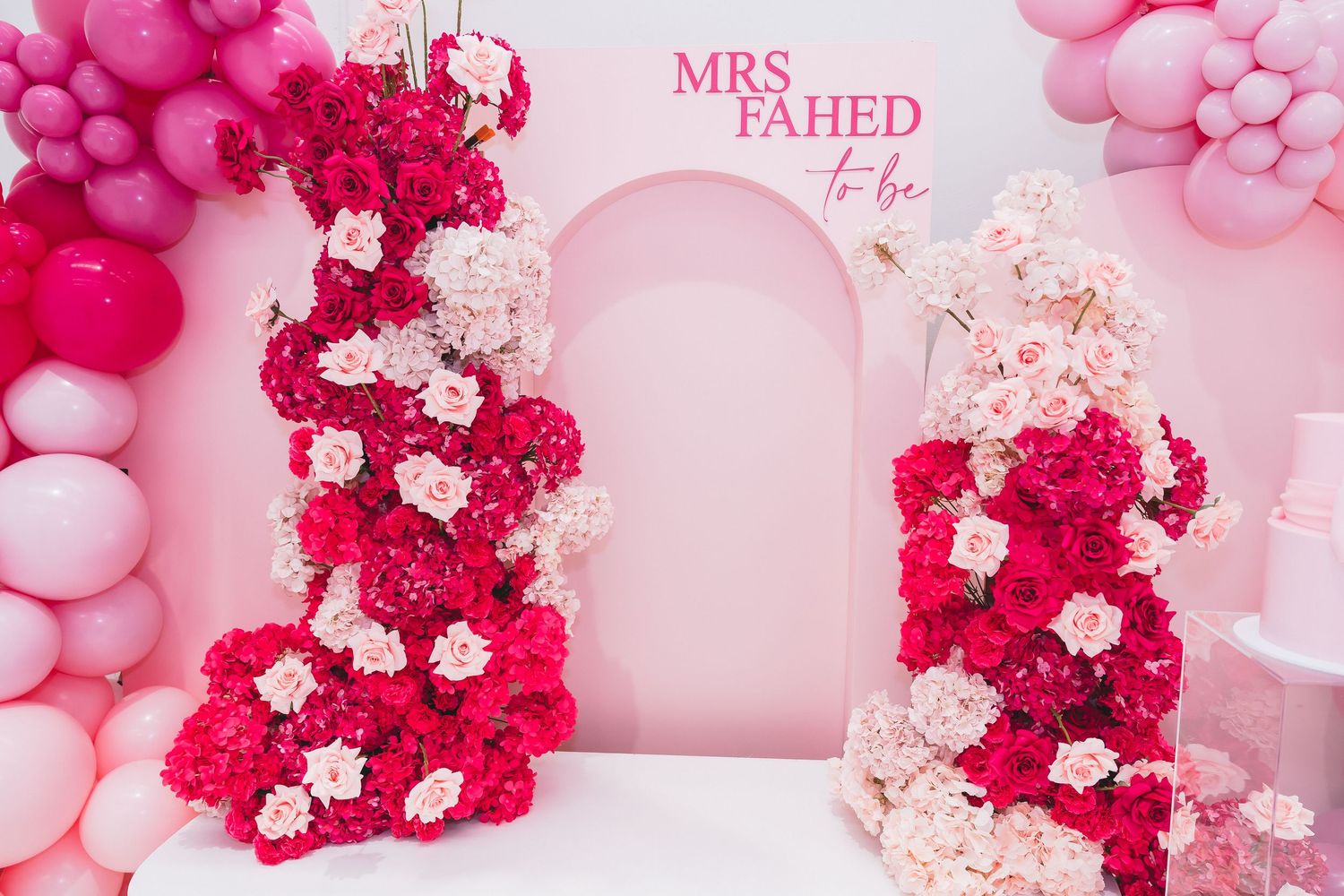 Pink bridal shower backdrop with floral columns, balloon arch, and Mrs Fahed To Be sign.