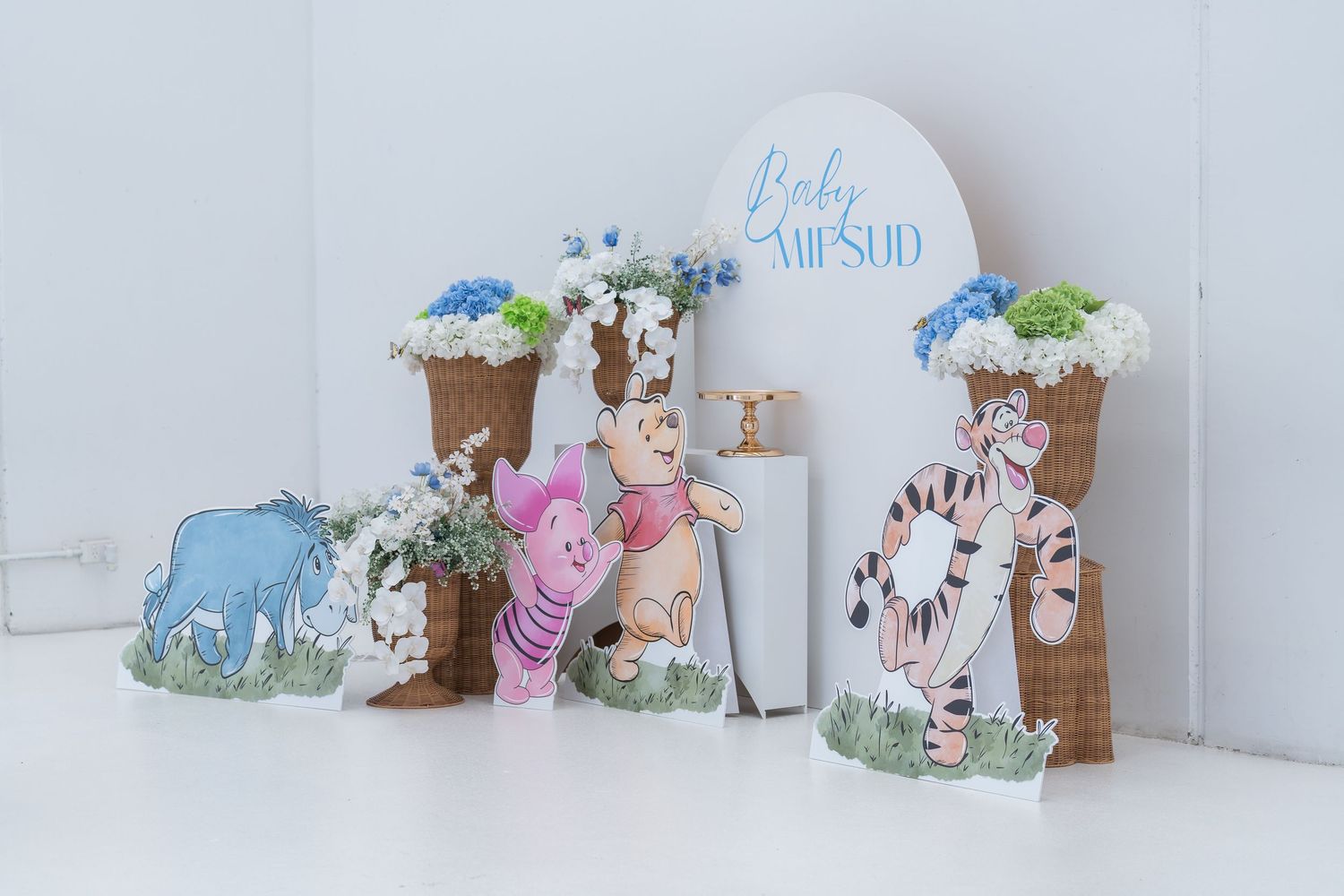 Winnie the Pooh baby shower decoration set featuring Pooh,Piglet,Tigger,and Eeyore cutouts with floral arrangements.