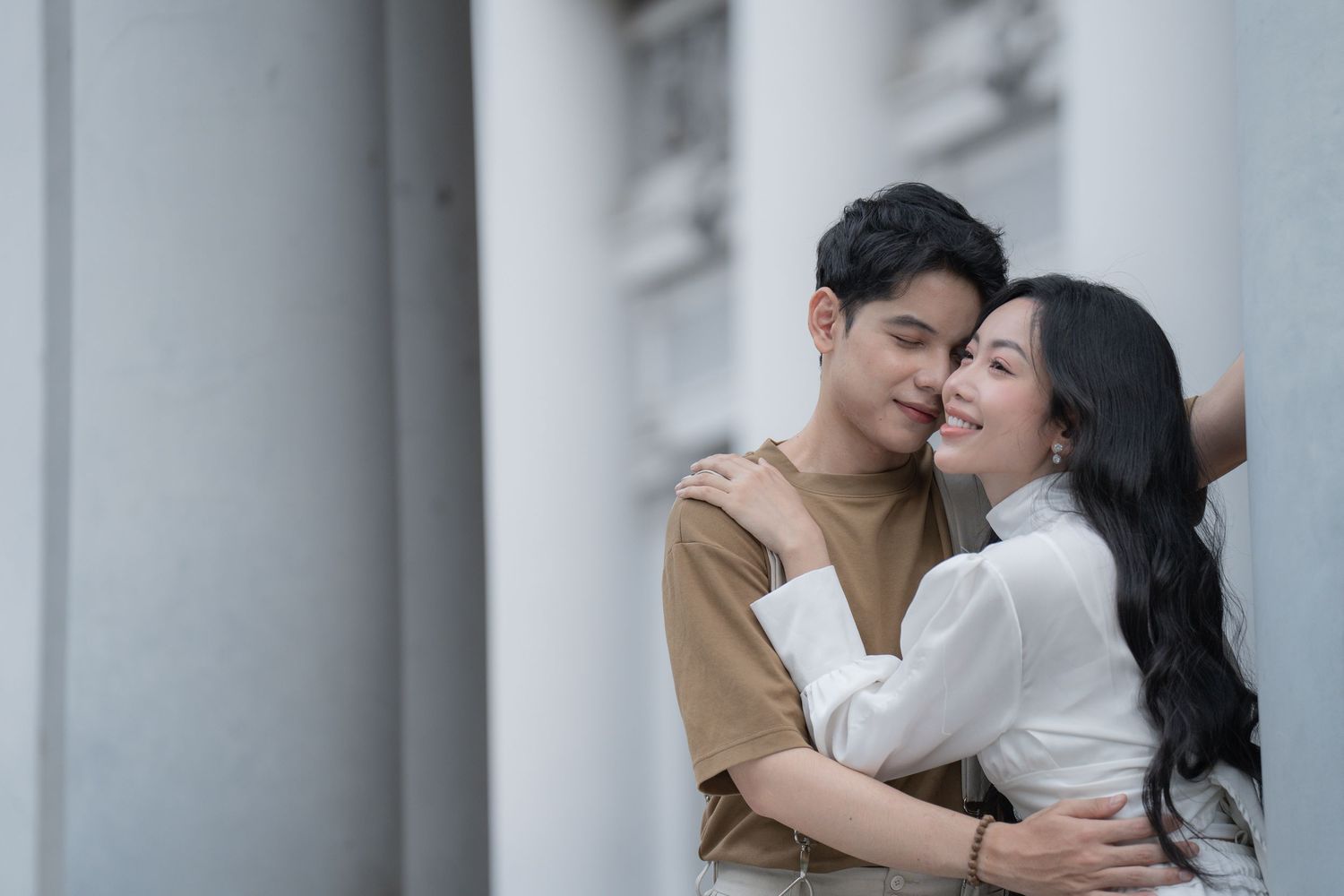 Tender moments captured between couple against white pillared backdrop.