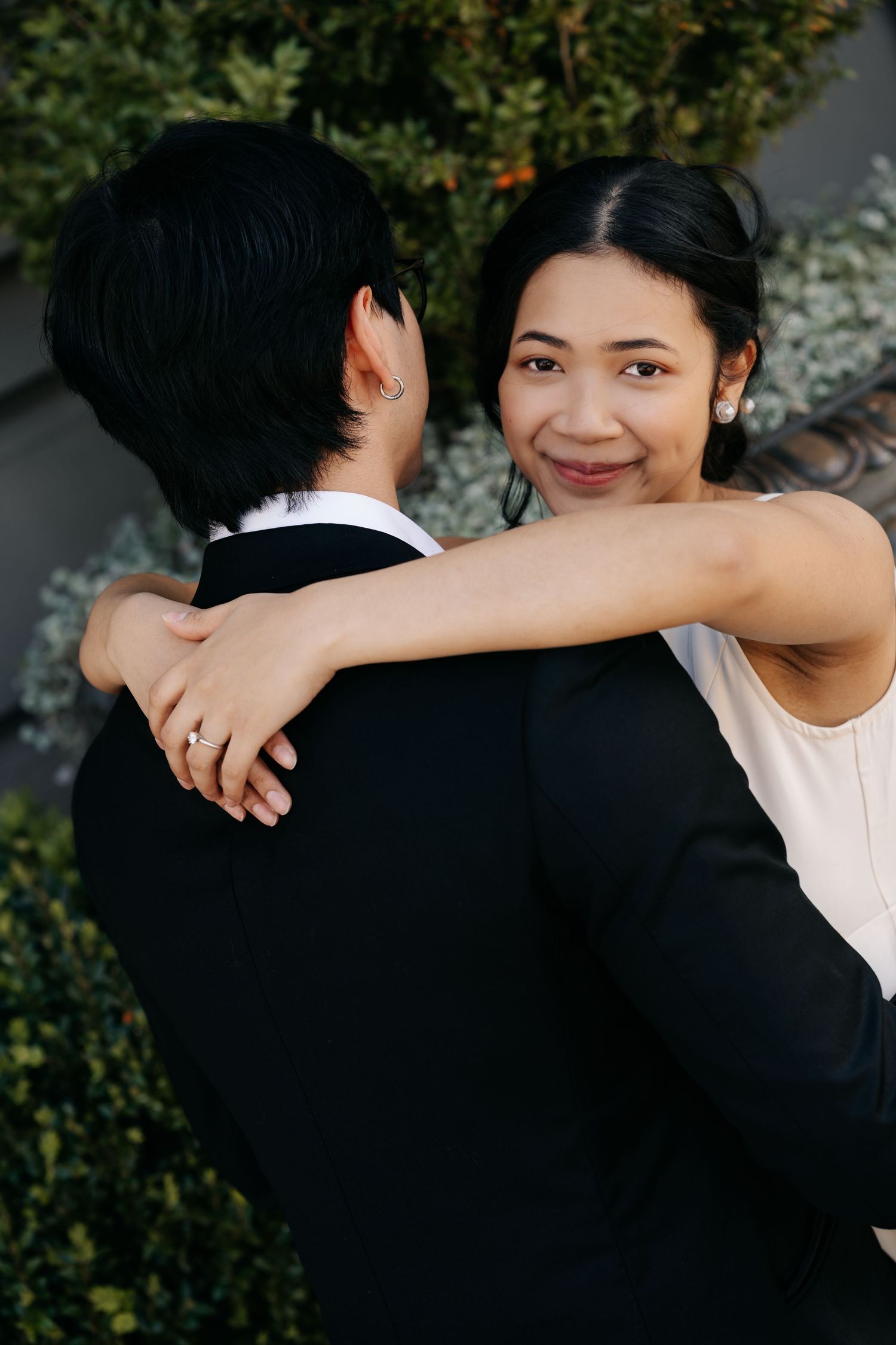 Tender embraces captured against lush greenery background in natural lighting.
