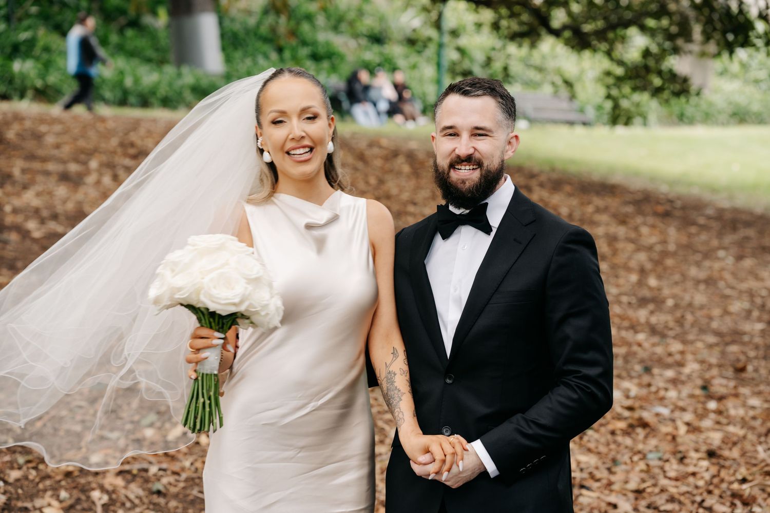 Joyful wedding portraits captured in a natural outdoor setting with trees in the background.