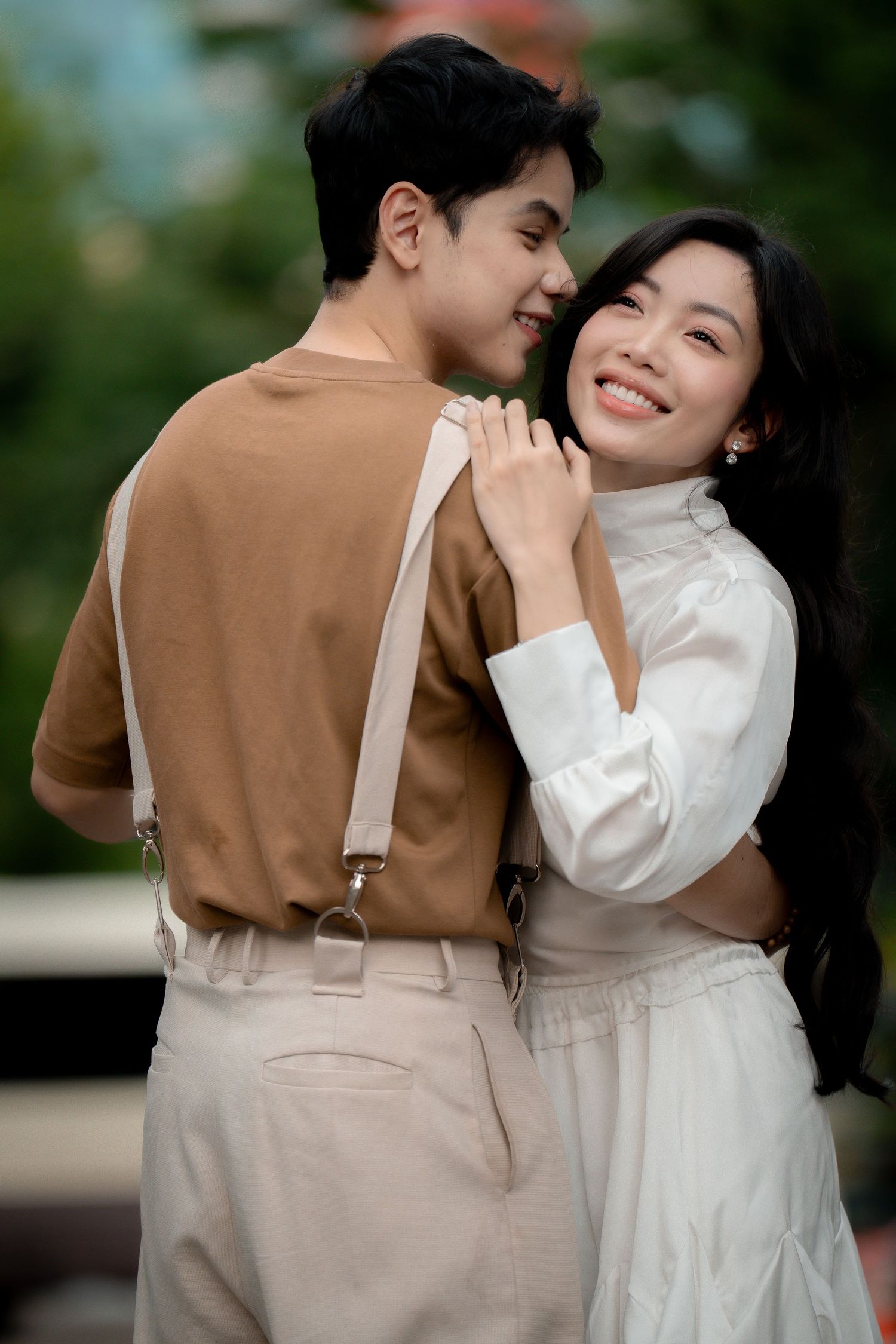 A romantic couple in brown and white outfits embrace and laugh together in a series of candid outdoor photos.