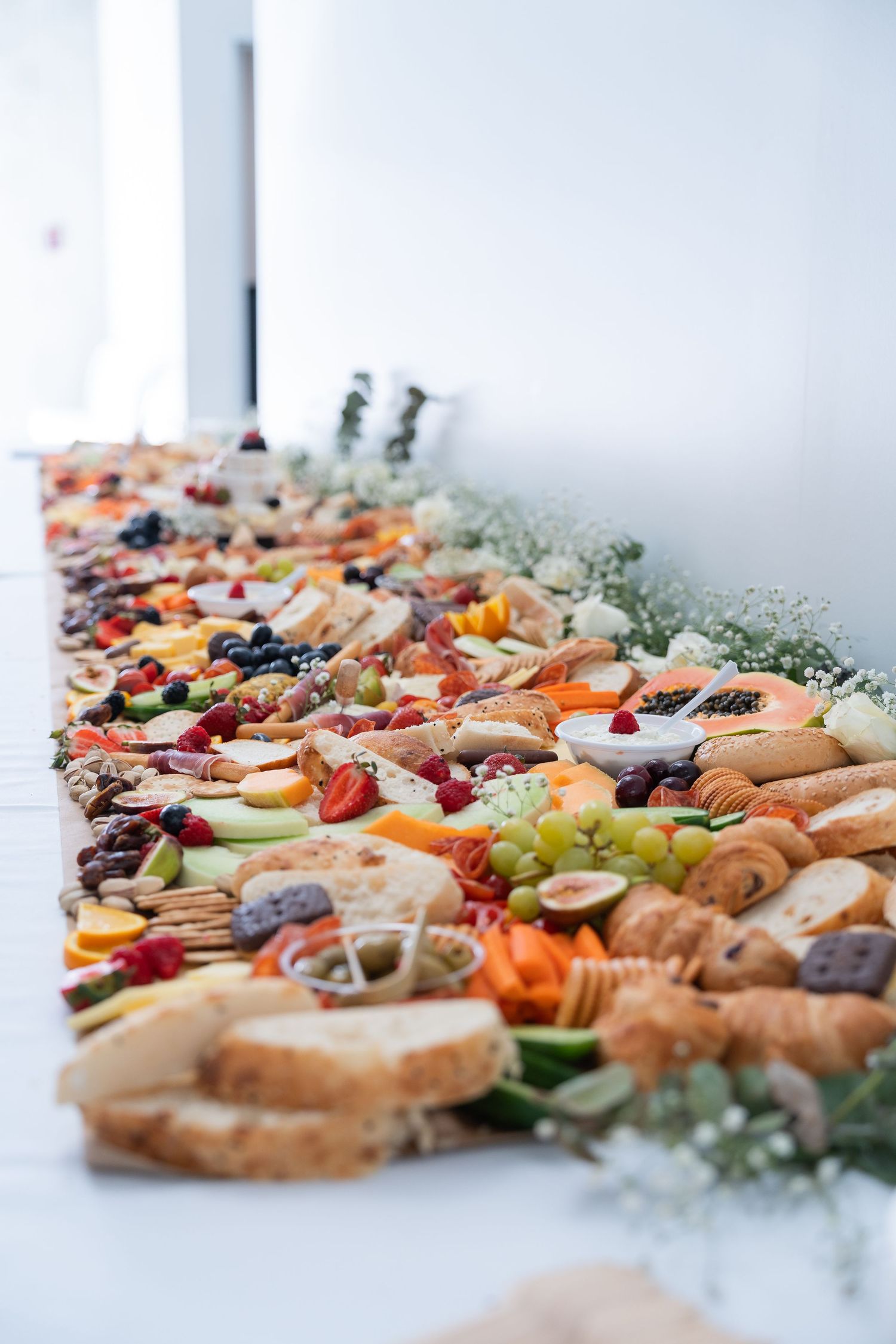 Elegant grazing table with fruits, cheeses, breads, and charcuterie arranged beautifully for a catered event.